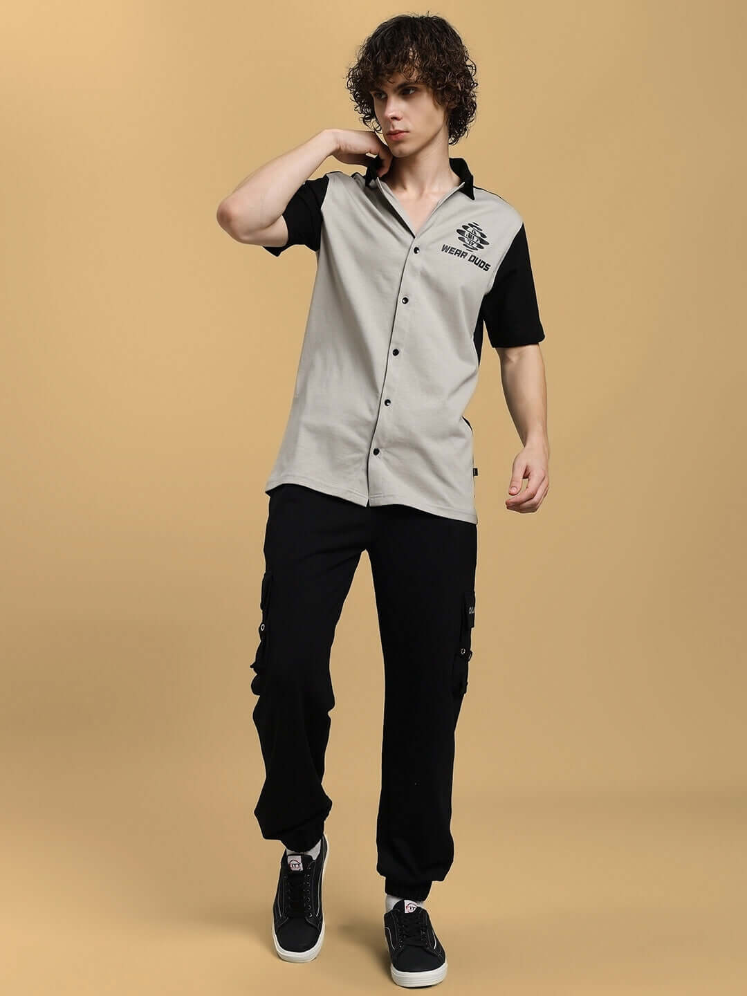 Model wearing black DUDS Commando Joggers and two-tone shirt against beige background