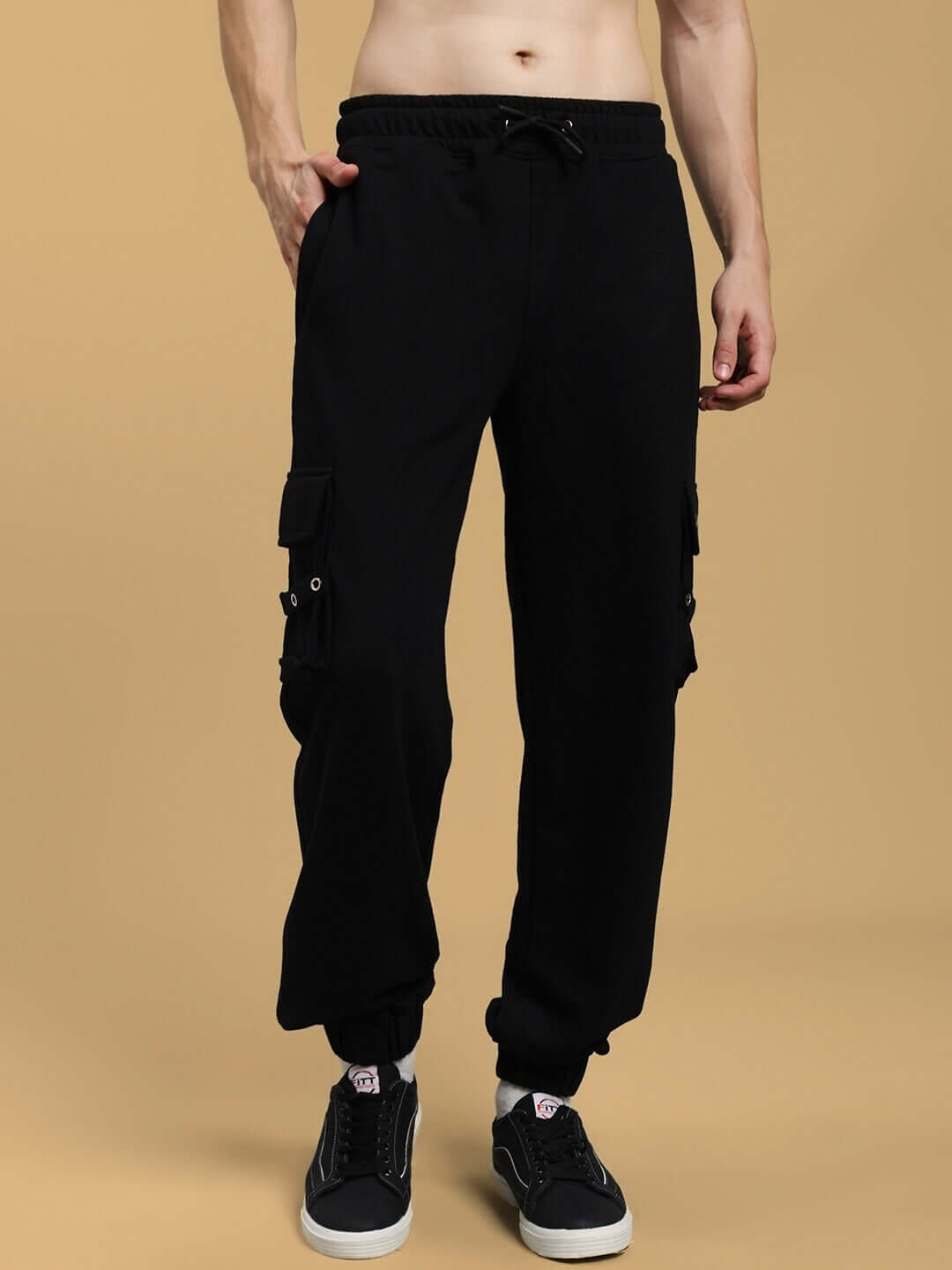 Model wearing DUDS COMMANDO black joggers with cargo pockets, showcasing a stylish fit available for custom orders; shipping 7-10 days.