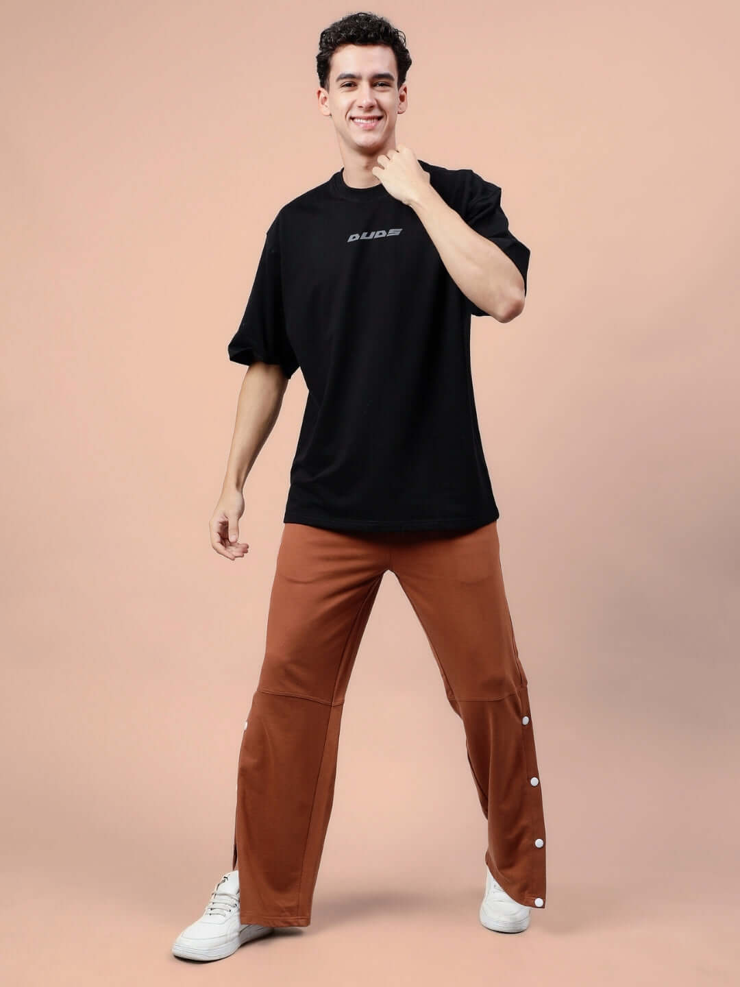 Man wearing DUDS Racer Joggers in brown, showcasing a casual and comfortable fit with side button design, paired with a black shirt.