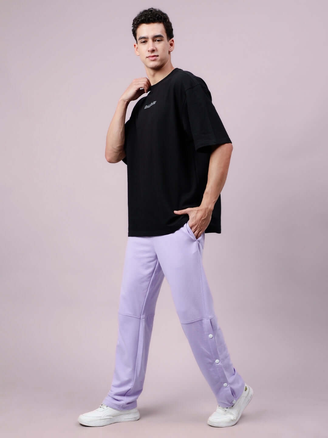 Model wearing DUDS Racer Joggers in lavender, styled with a black T-shirt and white sneakers, showcasing comfortable and stylish casual wear.