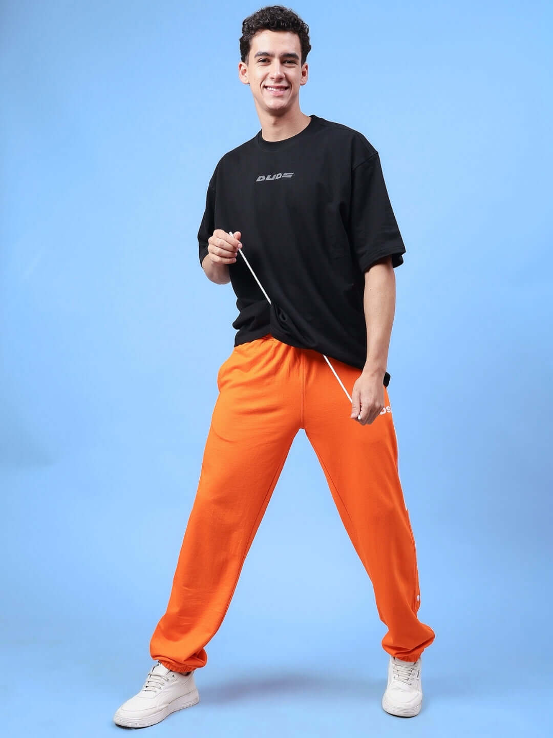 Man wearing DUDS Racer Joggers in Orange, showcasing comfortable fit and style against a blue background.