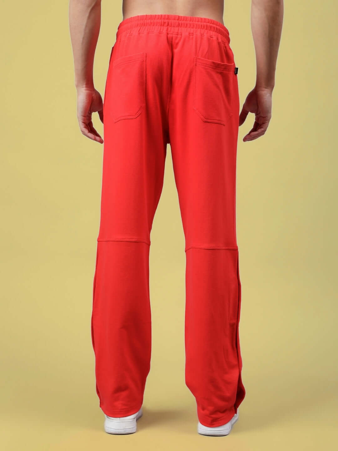 Model wearing DUDS Racer Joggers in red, showcasing back view with elastic waistband and patch pockets. Made-to-order by expert tailors.