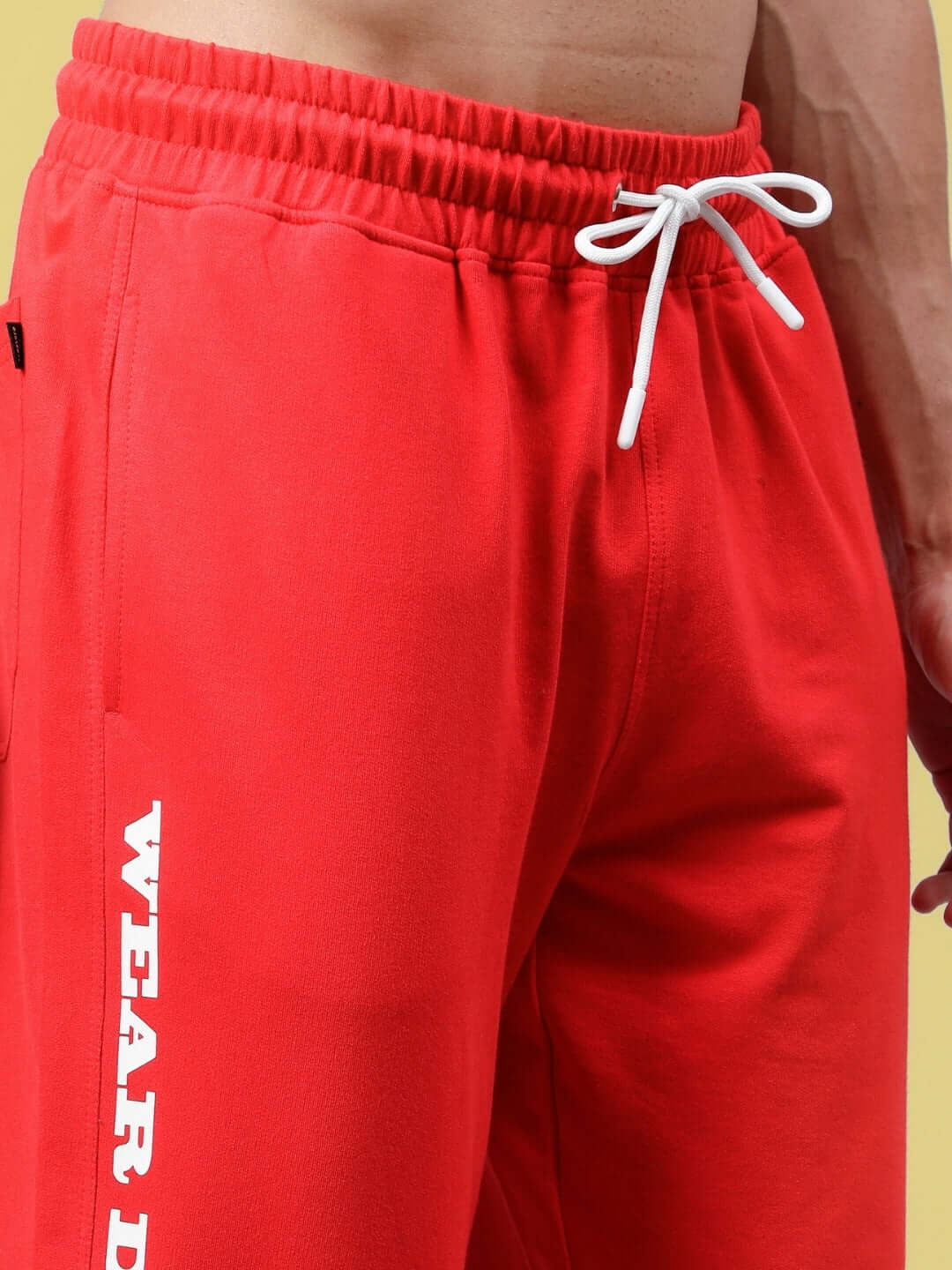 Close-up of red DUDS Racer Joggers with elastic waistband and drawstring, featuring "Wear D" slogan on the leg.