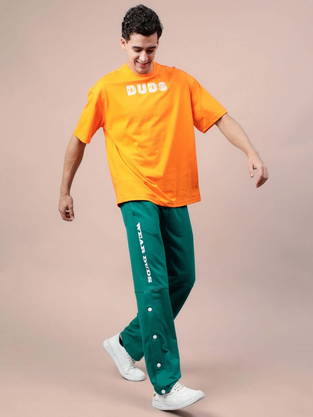 Man wearing DUDS Racer Joggers in teal green with an orange DUDS t-shirt, demonstrating style and comfort.
