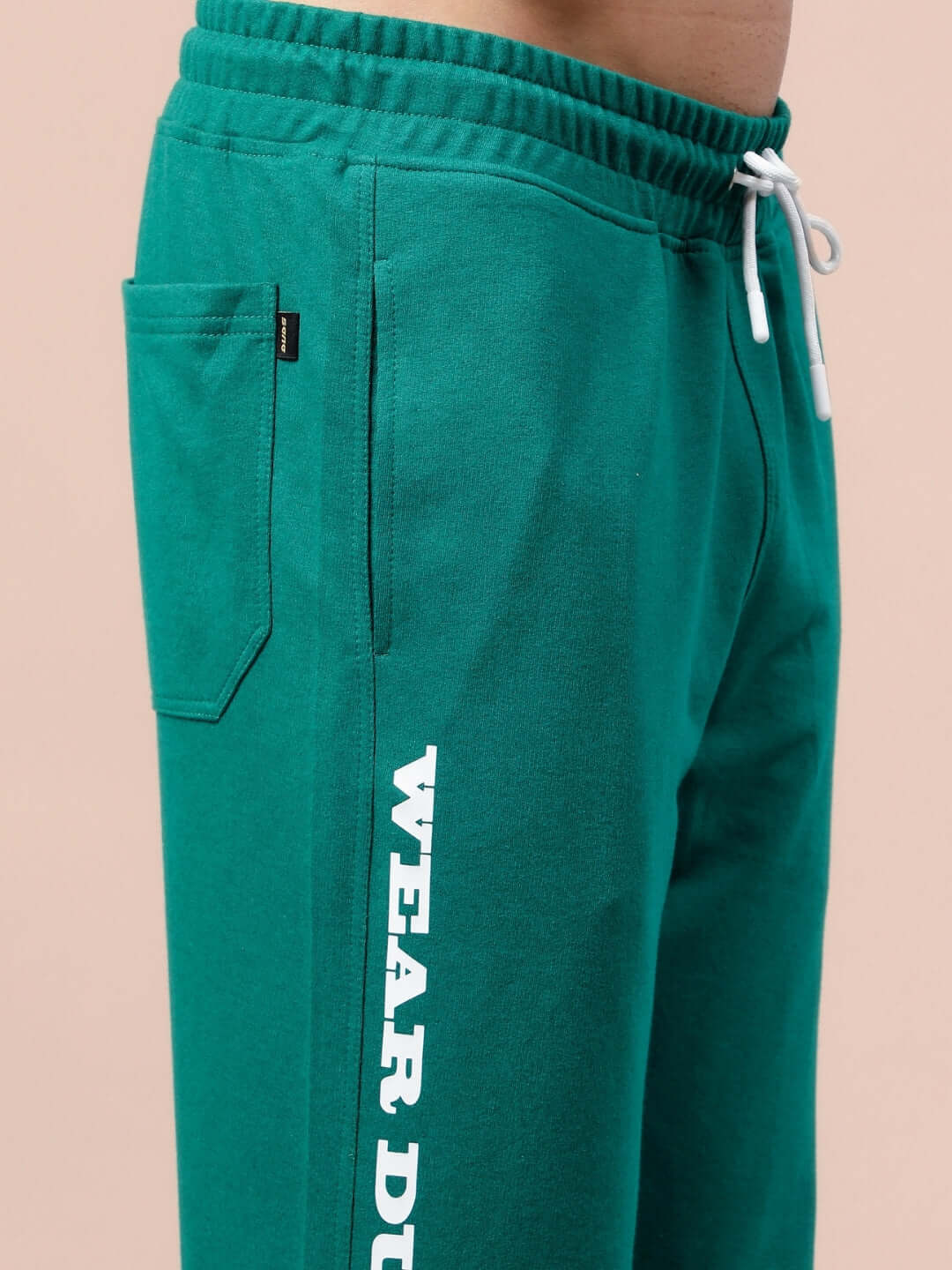 Model wearing DUDS Racer Joggers in teal green, emphasizing custom fit option and crafted by experienced tailors.