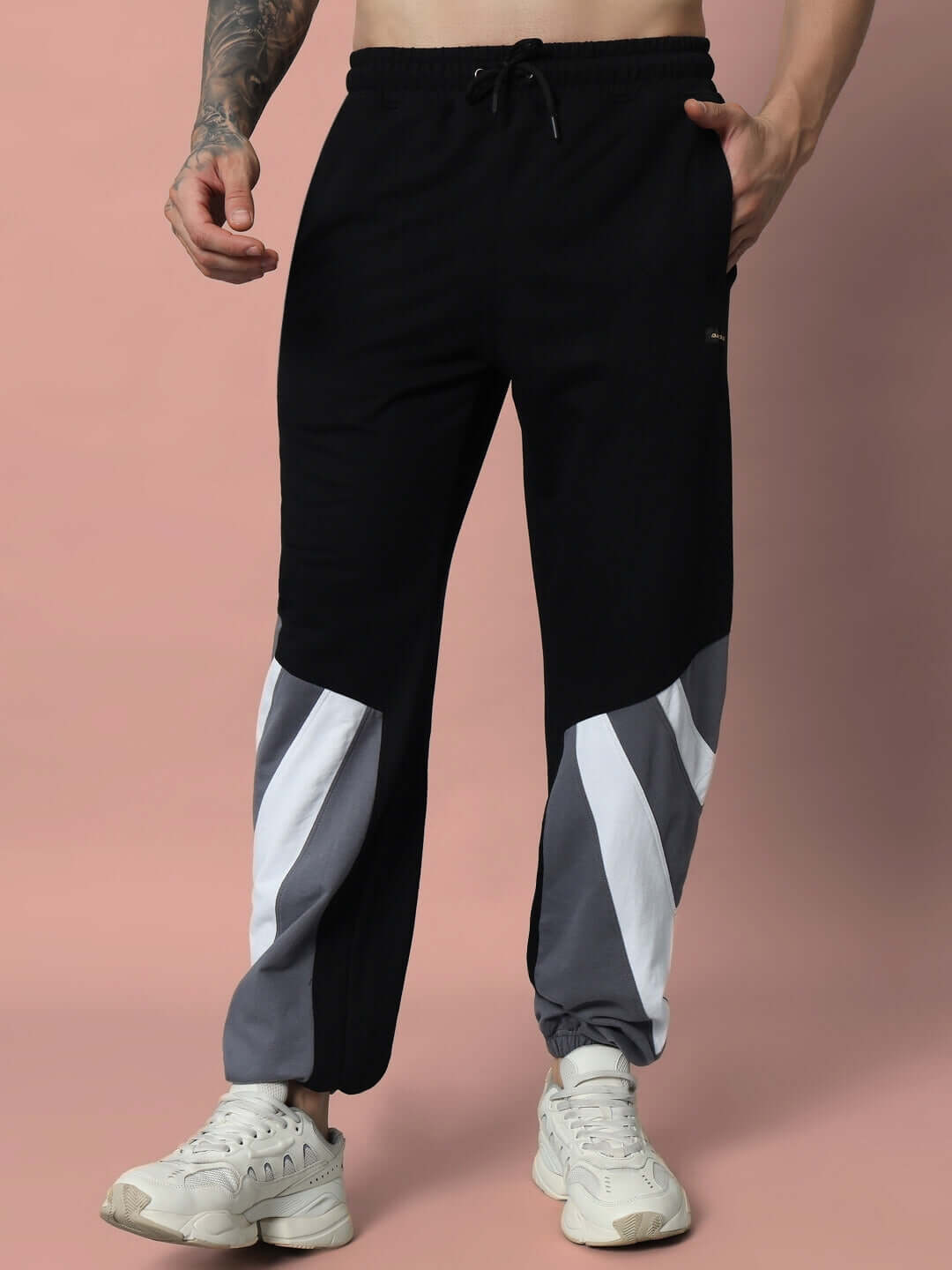 Model wearing DUDS DRAPE Relaxed Fit Joggers in black with gray and white accents, showcasing comfortable and customizable fit options.