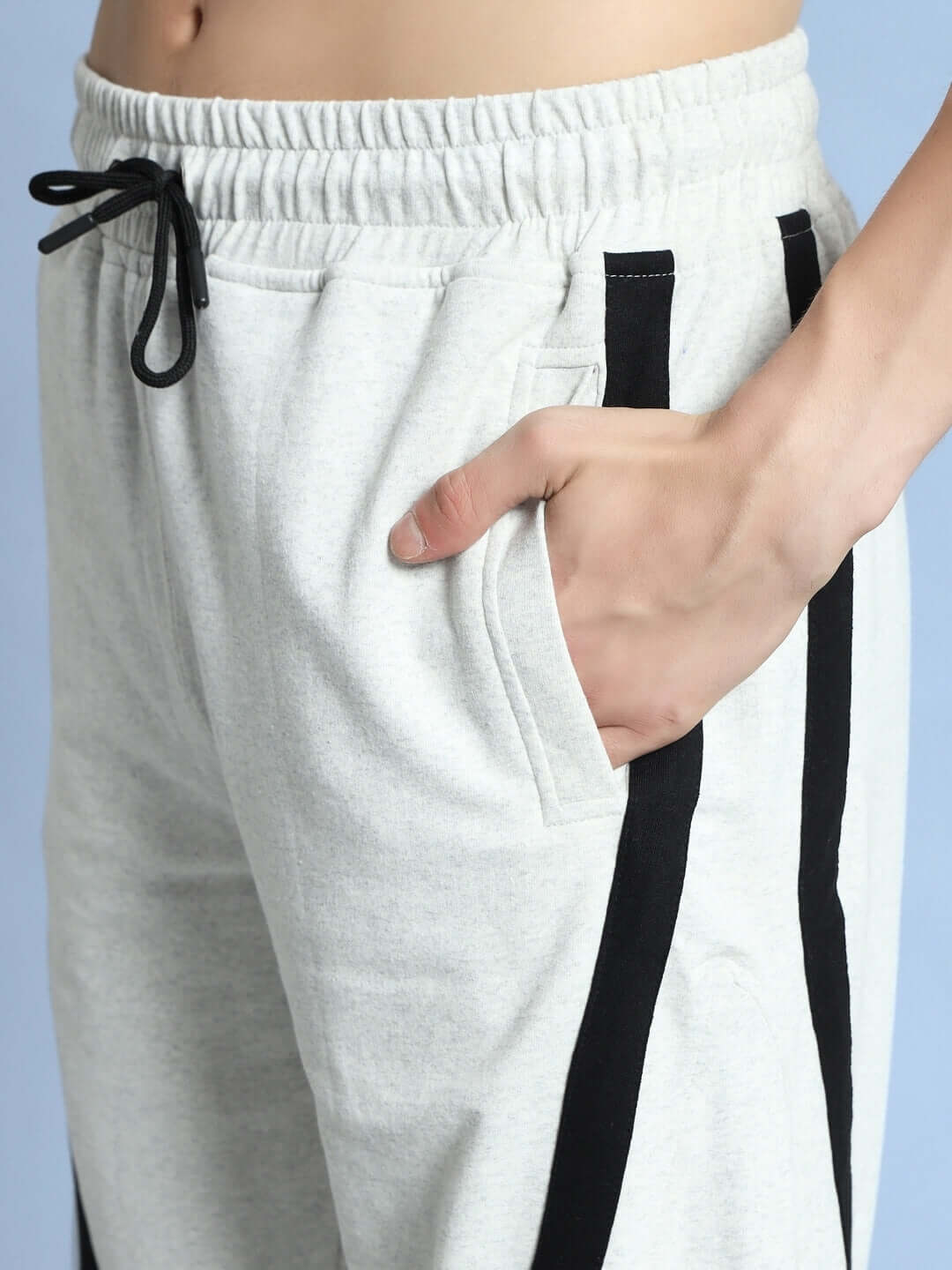 Close-up of a hand in the pocket of DUDS FRAME Joggers in melange grey with black side stripes, showcasing style and comfort.