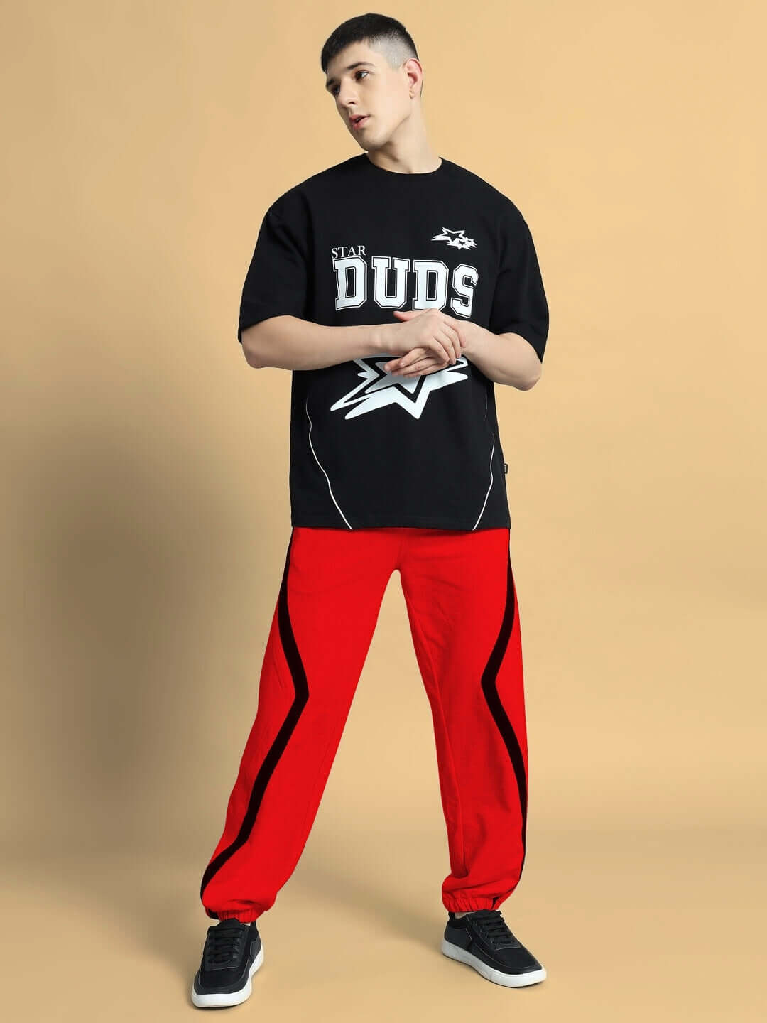 Model wearing DUDS red frame joggers, styled with black t-shirt, showcasing trendy casual wear.