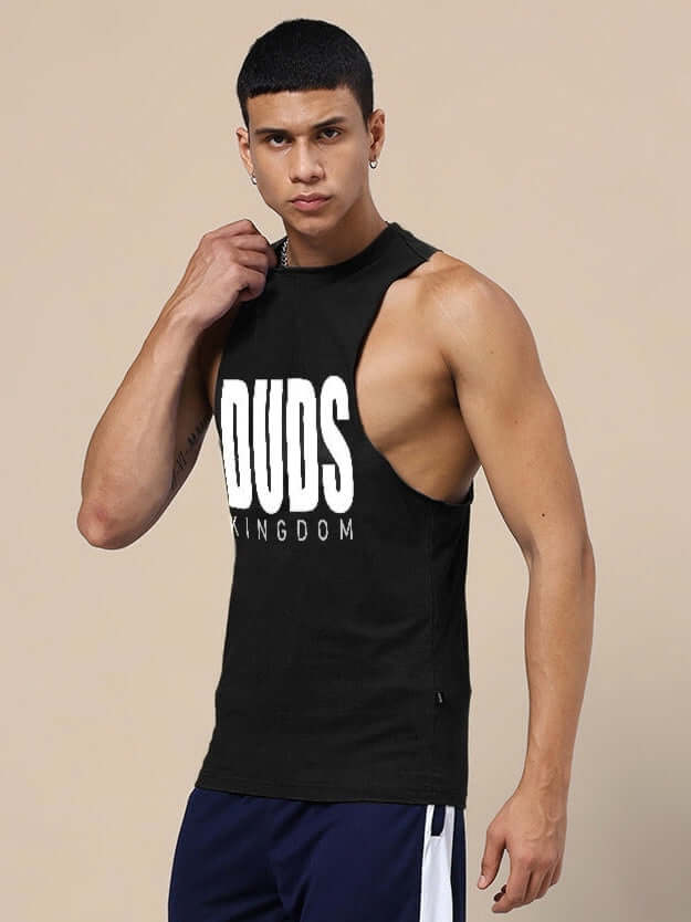 Man wearing DUDS KINGDOM GYM T-SHIRT BLACK, sleeveless design, standing pose in athletic setting.