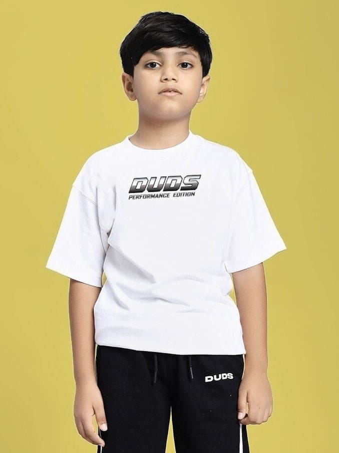 Young boy wearing DUDS PERFORMANCE T-SHIRT FOR BOYS AND GIRLS WHITE against a yellow background