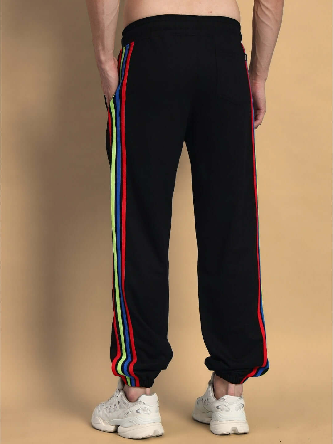 Back view of DUDS Rainbow Colorful Stripe Joggers in black featuring multicolored side stripes, worn by model with white sneakers.