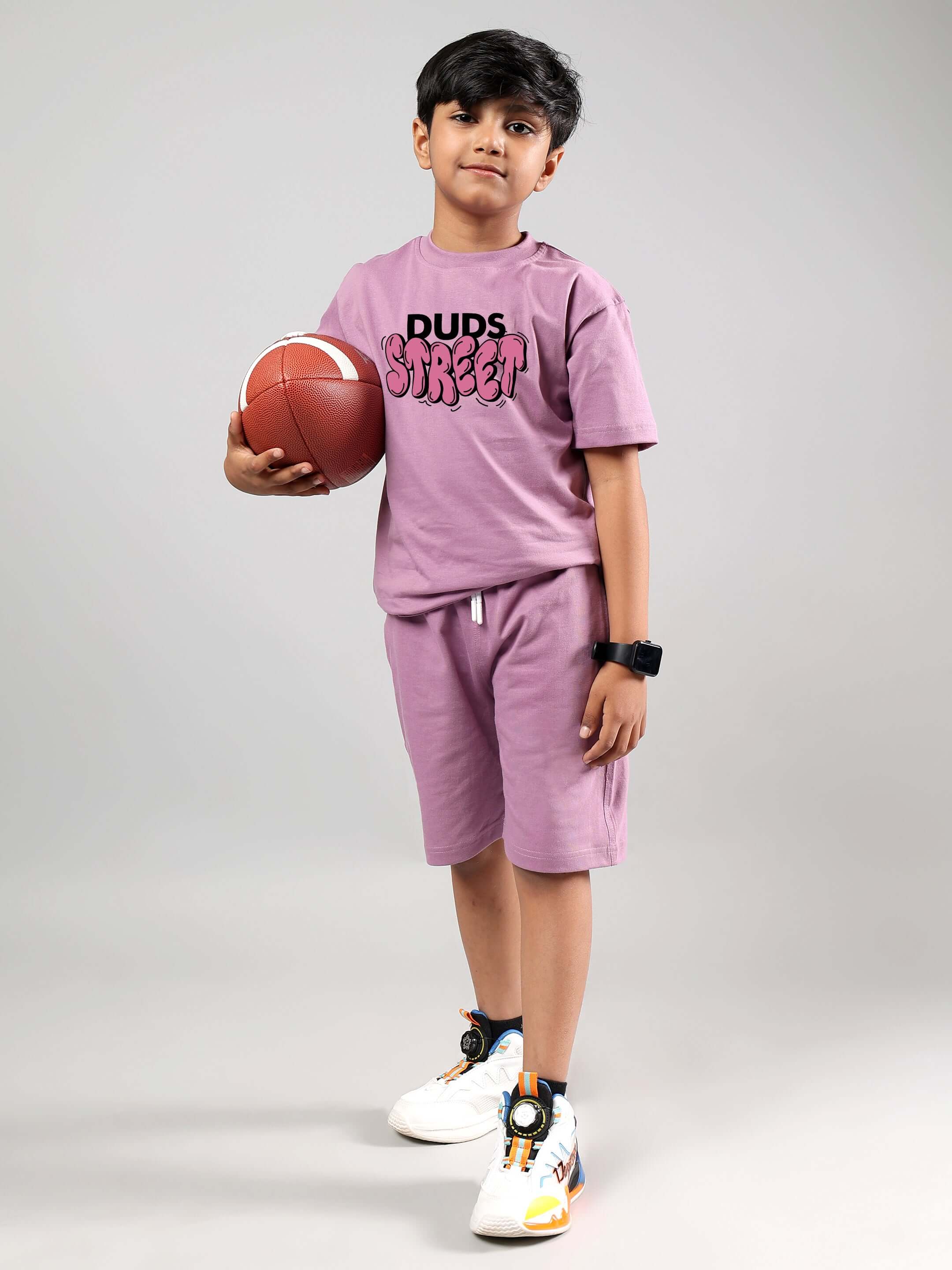 Boy wearing DUDS Street printed t-shirt in plum purple holding a basketball, showcasing casual style for boys and girls.