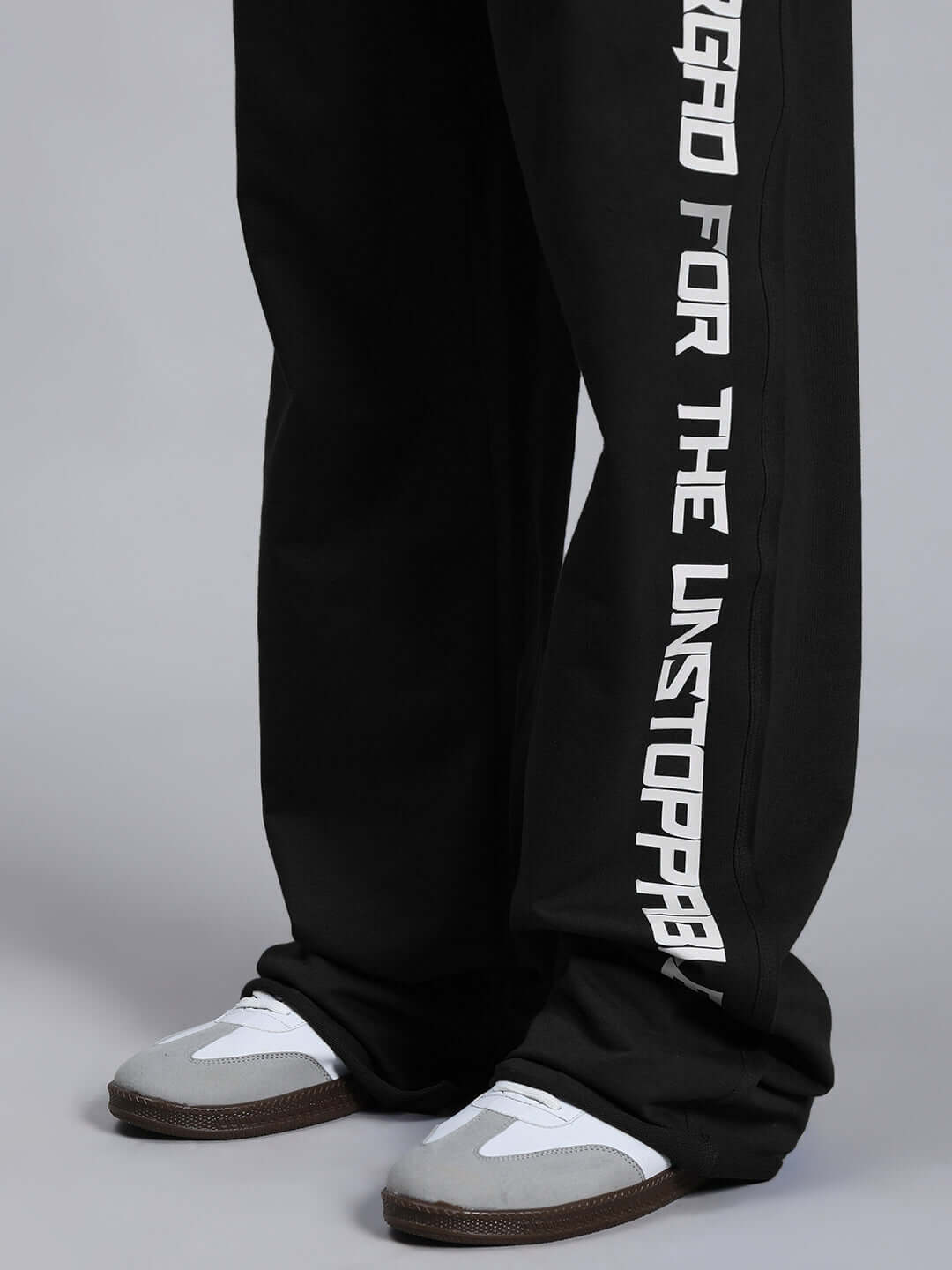 Close-up of DUDS SWIFT JOGGER COTTON TERRY BLACK showcasing leg design and casual sneakers.