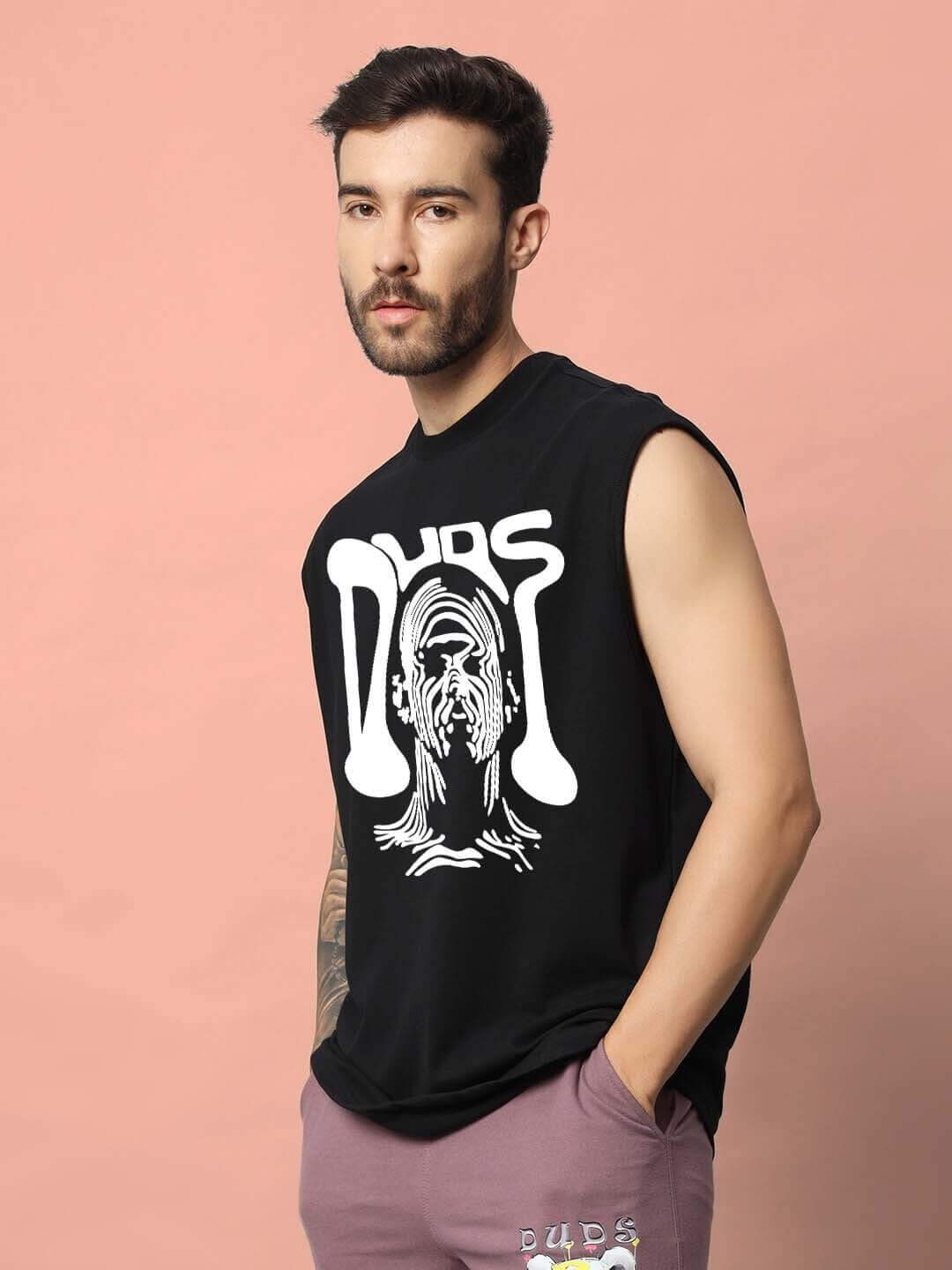Man wearing a black DUDS TASKA gym t-shirt with bold graphic design, customizable fit option available.
