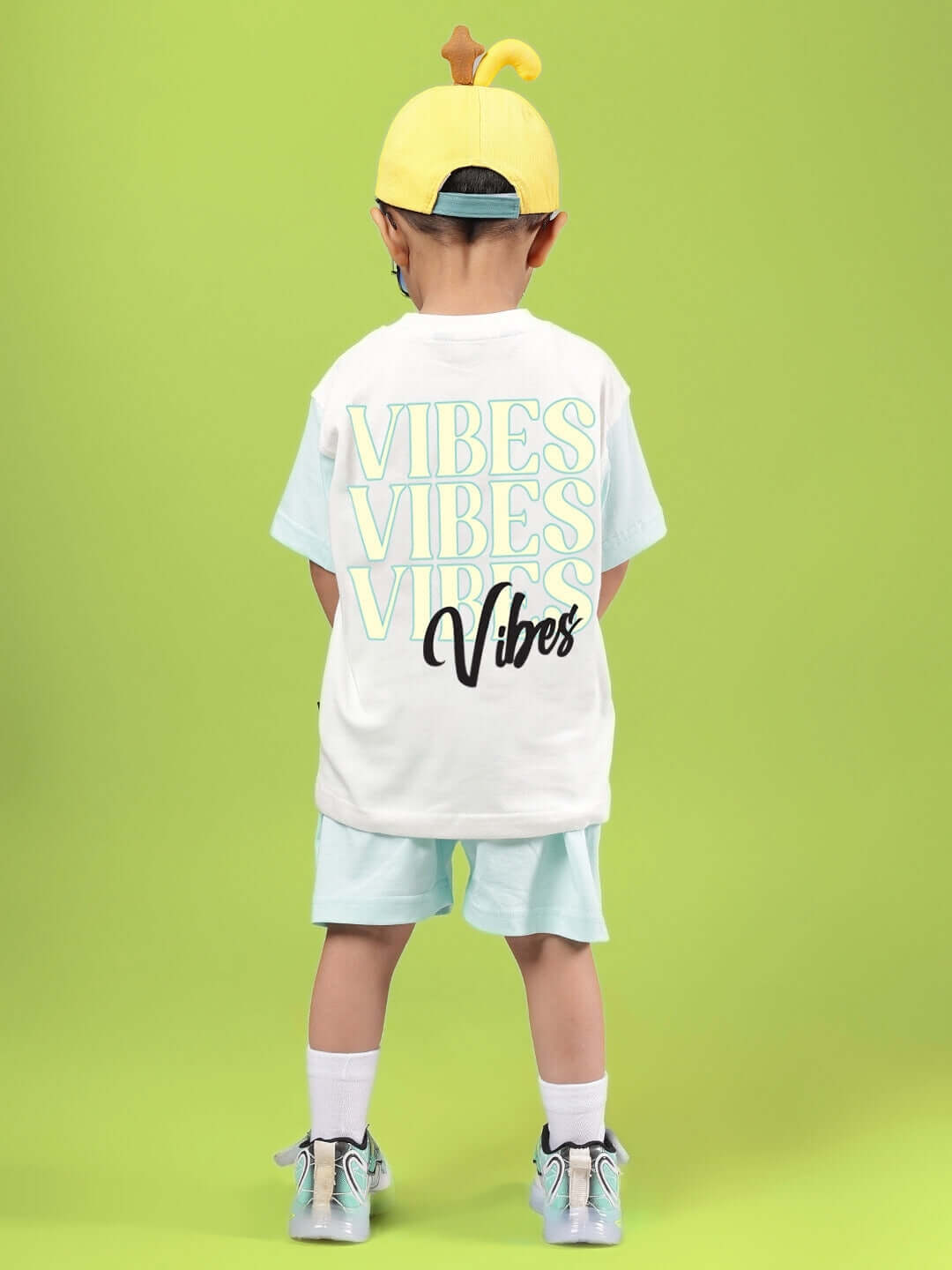 Boy wearing DUDS VIBES CO-ORD FOR BOYS & GIRLS OFF WHITE-BLUE with vibrant text print on green background.