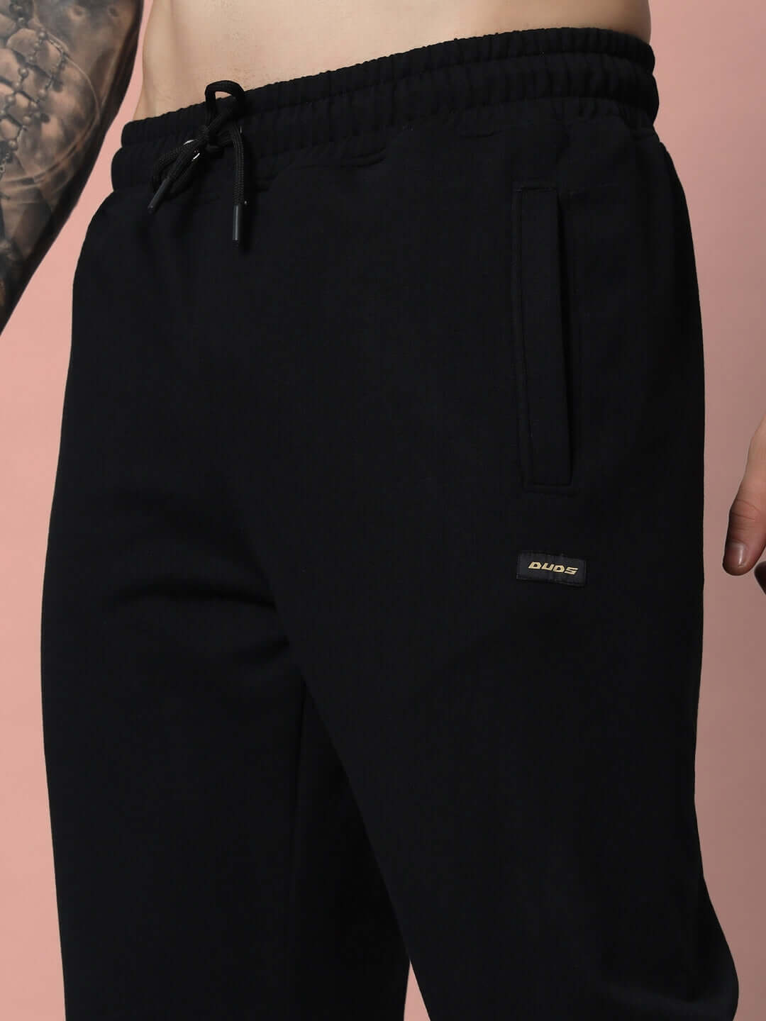 Close-up of DUDS Drape Relaxed Fit Joggers in black, showcasing tailored craftsmanship and customizable fit option.