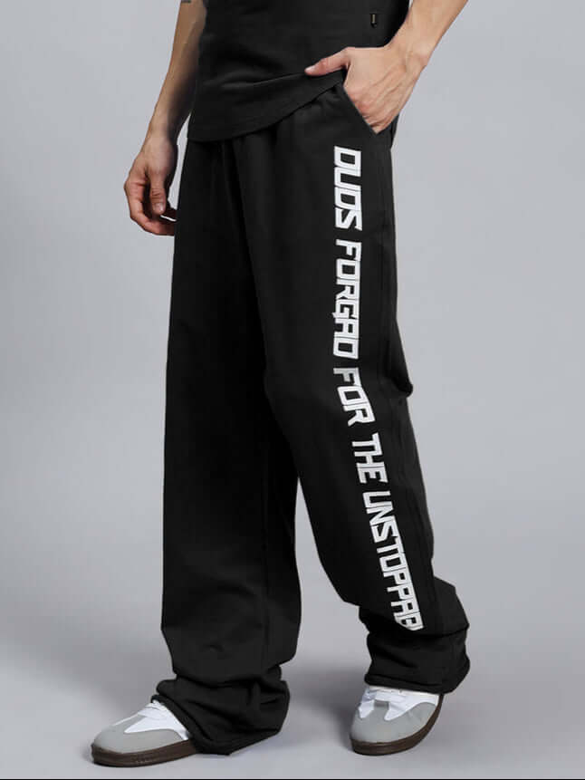 DUDS SWIFT JOGGER COTTON TERRY BLACK pants with bold side lettering, worn by a model showcasing style and comfort.