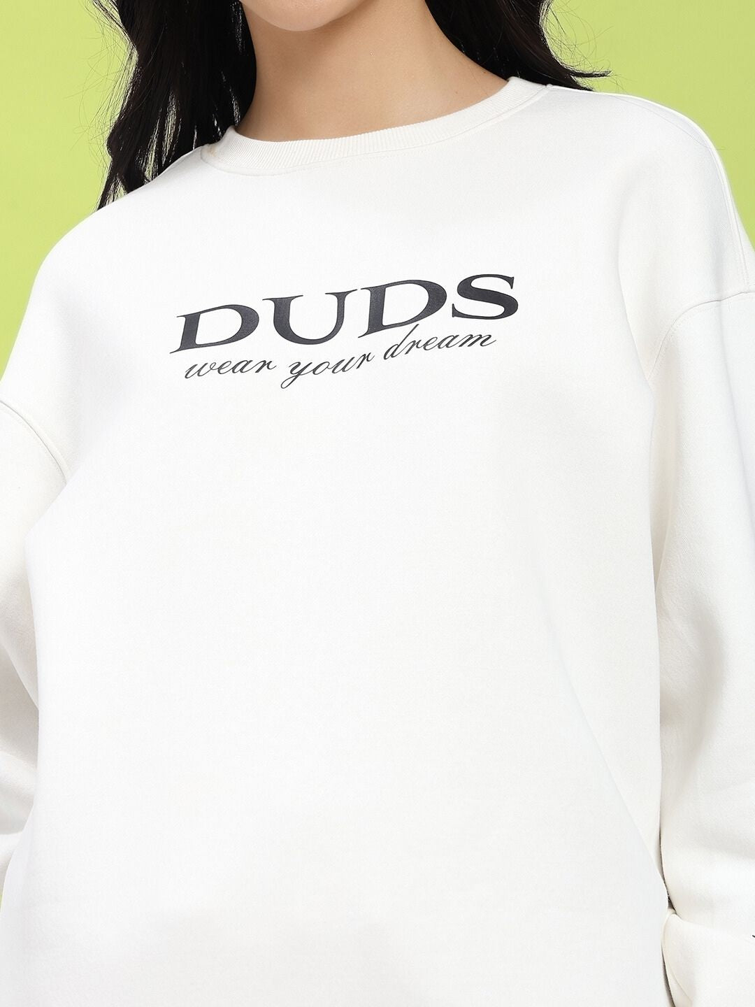 Model wearing off-white fleece with 'DUDS wear your dream' text print, showcasing casual streetwear style.
