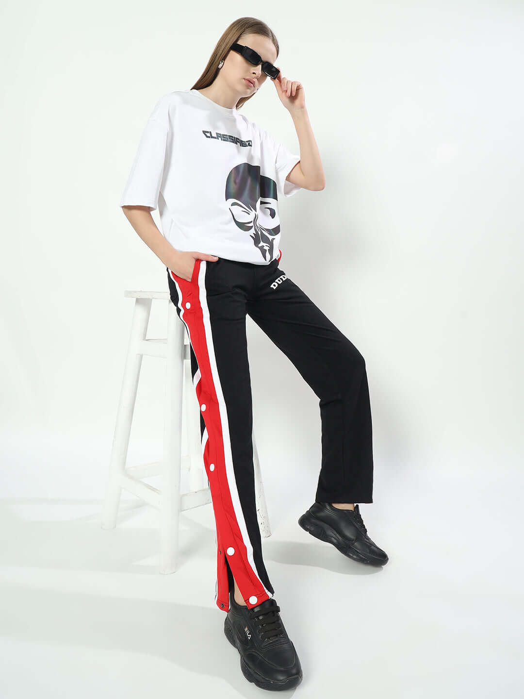 Woman wearing DUDS Magician Jogger for Women in Black with red stripe and snap buttons, paired with black sneakers and sunglasses.