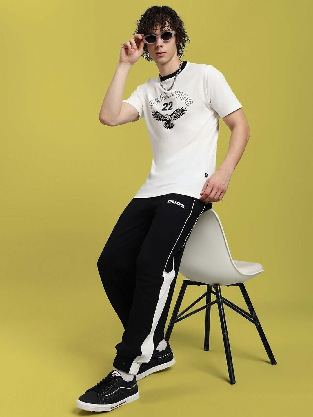 Model wearing Eagle Wings Regular Fit White T-Shirt in premium cotton, styled with black joggers against a yellow background.