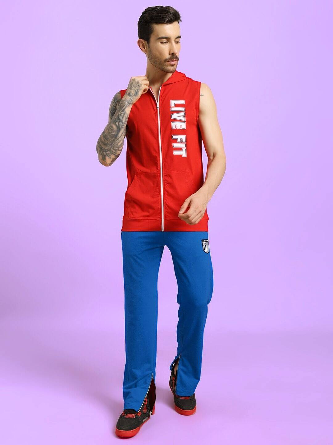 Model wearing ELEGANT RELAXED-FIT JOGGERS BLUE paired with a red sleeveless jacket on a purple background.