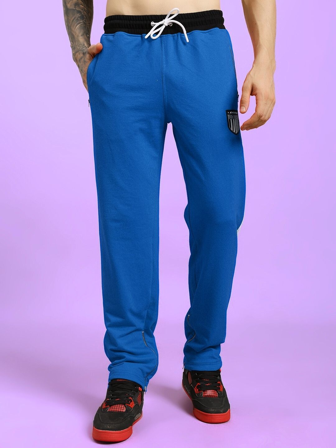 ELEGANT RELAXED-FIT JOGGERS BLUE with black waistband on model against purple background.