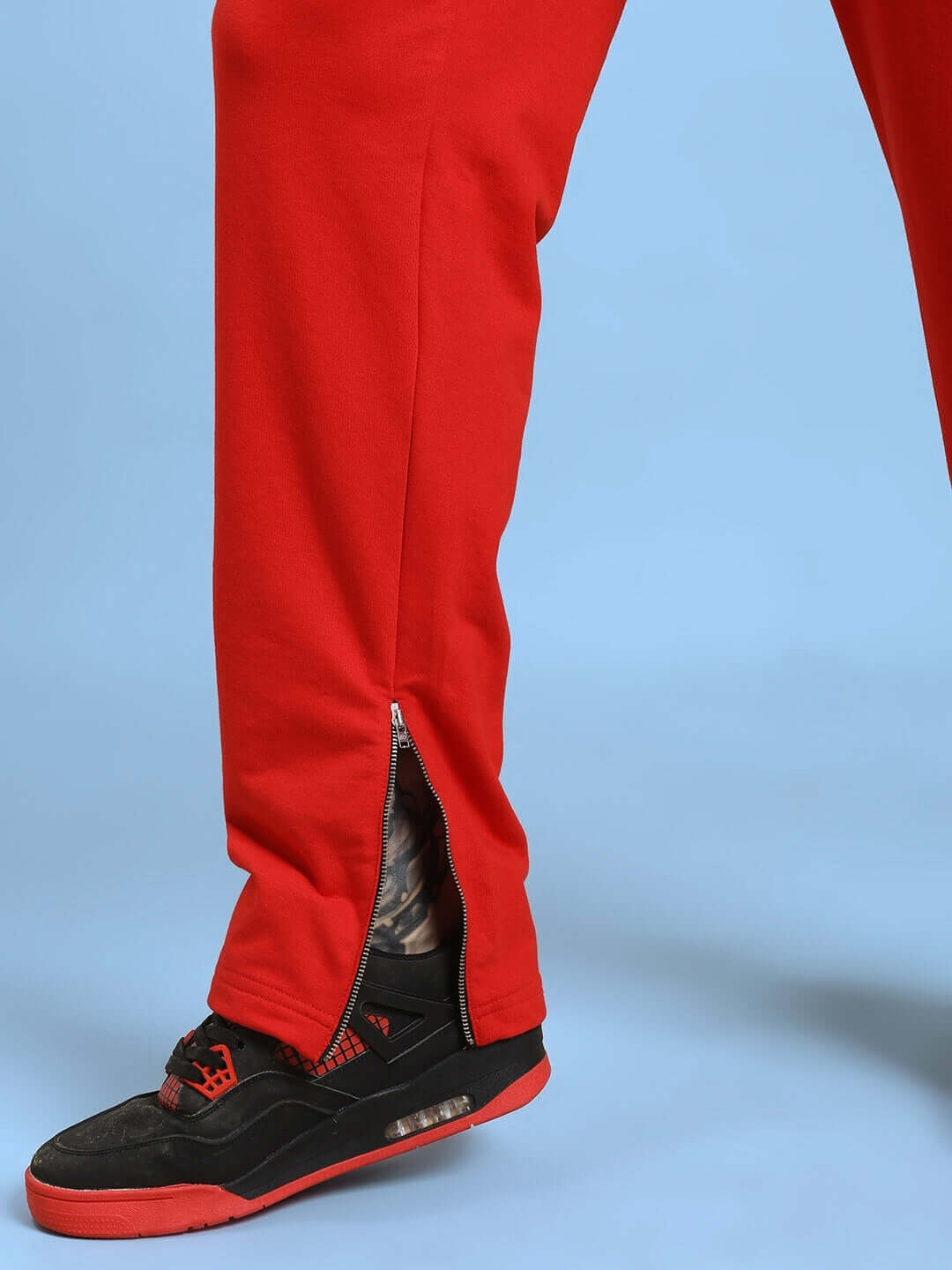 ELEGANT RELAXED-FIT JOGGERS RED showcasing side zipper detail with black and red sneakers.