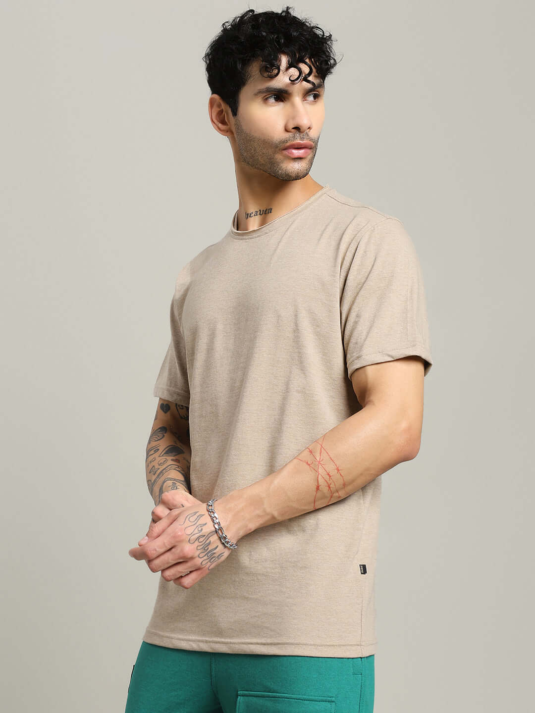 Man wearing ELEX REGULAR FIT T-SHIRT BEIGE in a stylish pose, showcasing the comfort and versatility of the premium cotton fabric.