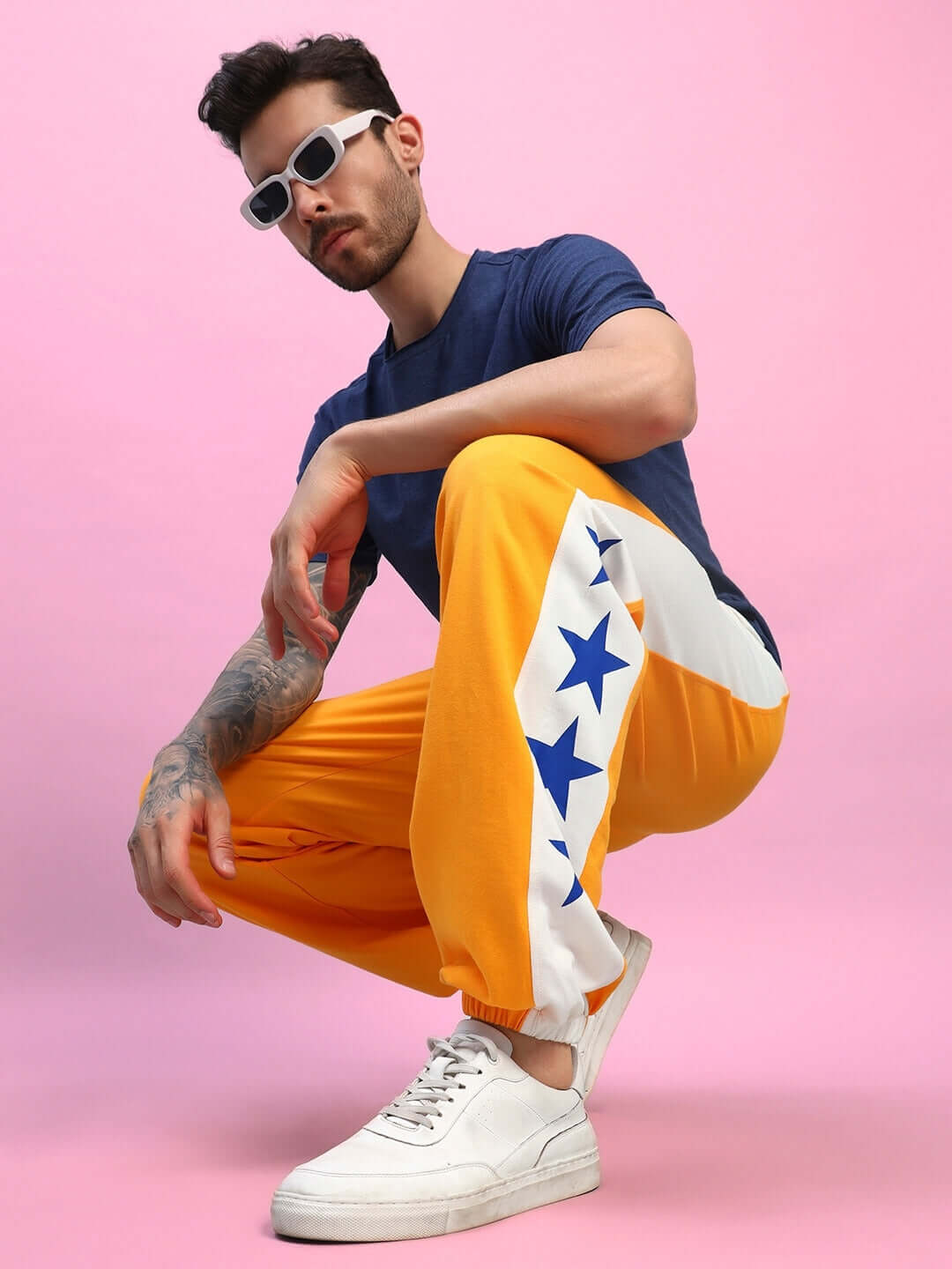 Model wearing ELEX REGULAR FIT T-SHIRT NAVY BLUE paired with vibrant star-patterned pants, showcasing a trendy casual outfit.