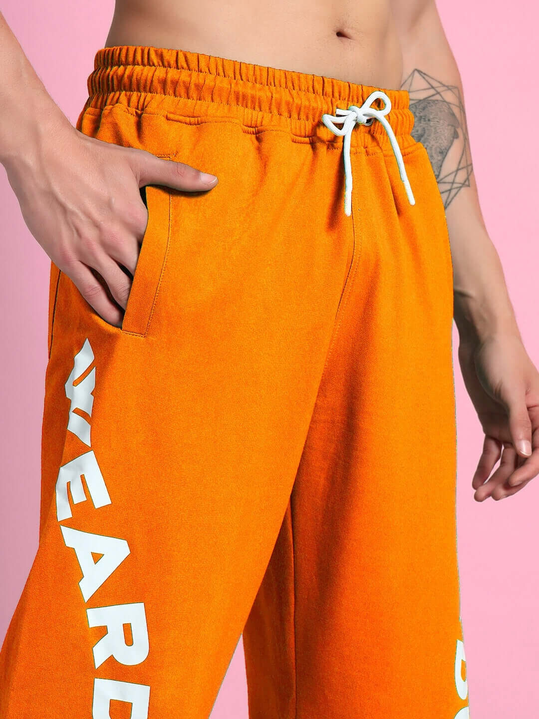 Person wearing ELLEN RELAXED FIT JOGGER ORANGE with side lettering against pink background