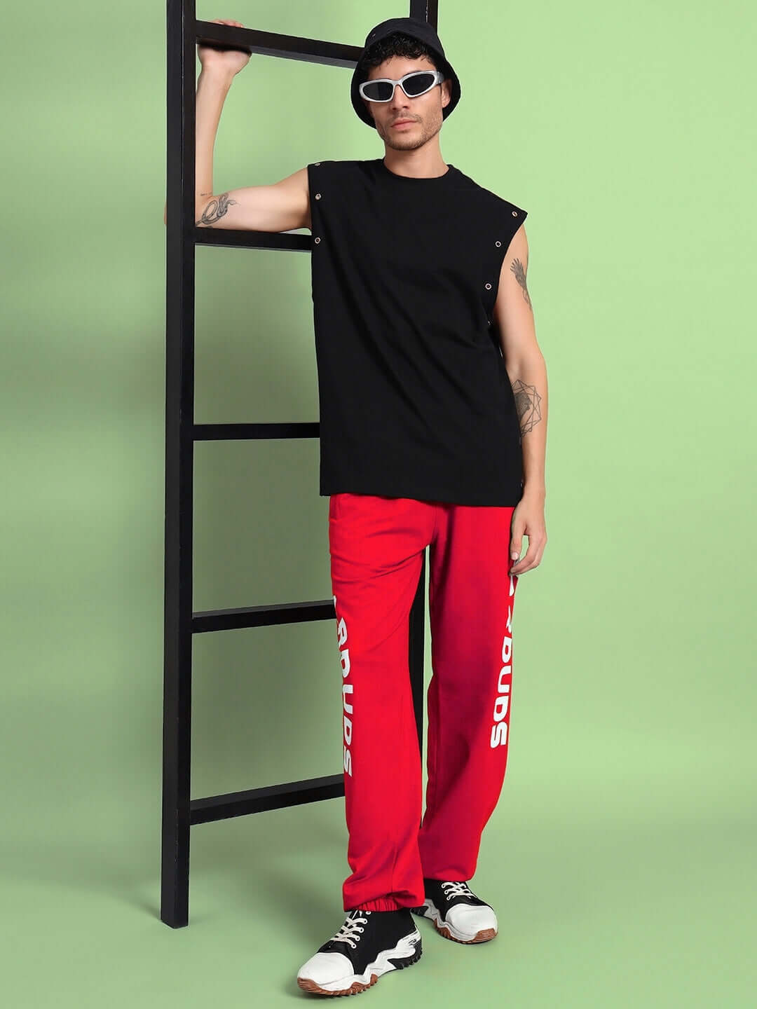 Man wearing Ellen Relaxed Fit Jogger in red stands against a ladder, showcasing trendy streetwear style.