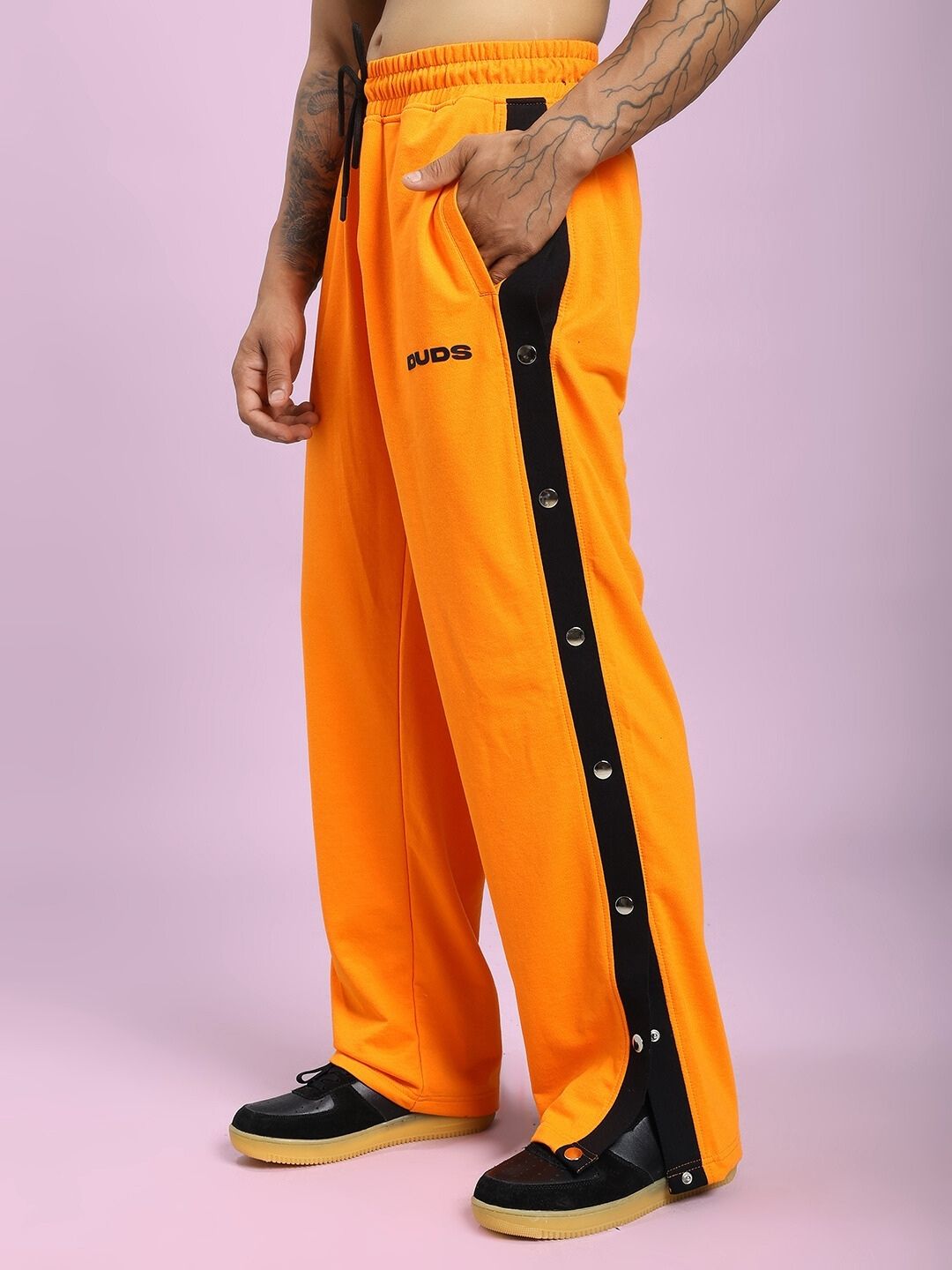 Model wearing EMBER BOLT SIDE JOGGER IN ORANGE with black side stripe detailing, showcasing bold color and relaxed fit in casual wear.