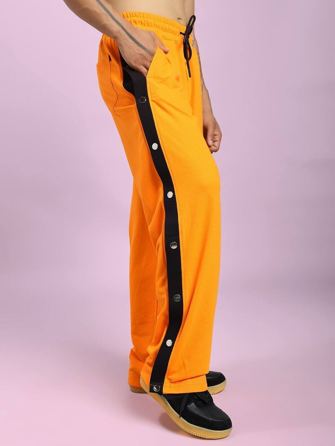 Vibrant EMBER BOLT SIDE JOGGER IN ORANGE with sleek side stripe detailing, showcased on a modern, colorful background.