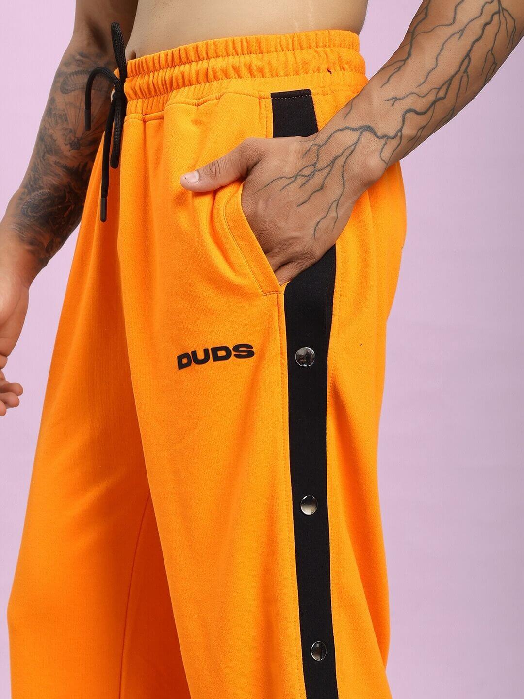 Model wearing EMBER BOLT SIDE JOGGER IN ORANGE with black side stripe and button detail