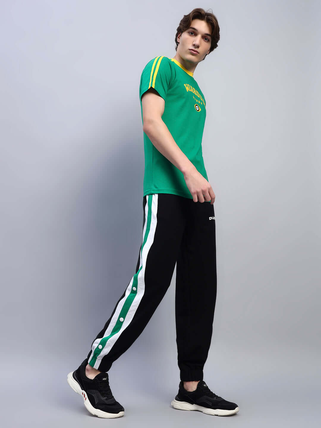 Man wearing EMIRATI STRIPES JOGGERS BLACK-GREEN with green side stripes, showcasing sporty style and comfort.