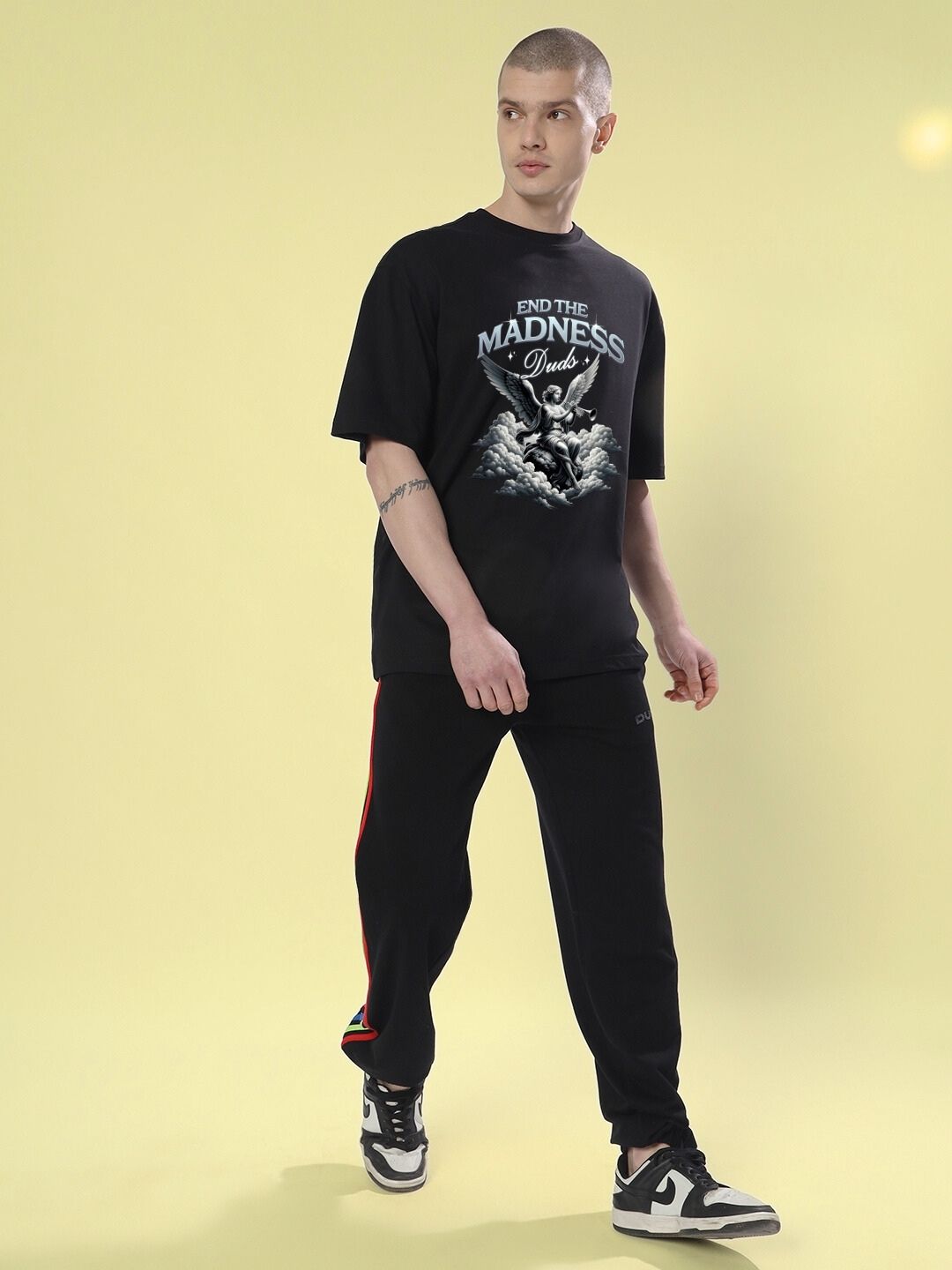 Model wearing END THE MADNESS OVER-SIZED T-SHIRT BLACK with streetwear graphic, showcasing relaxed fit and rebellious style.