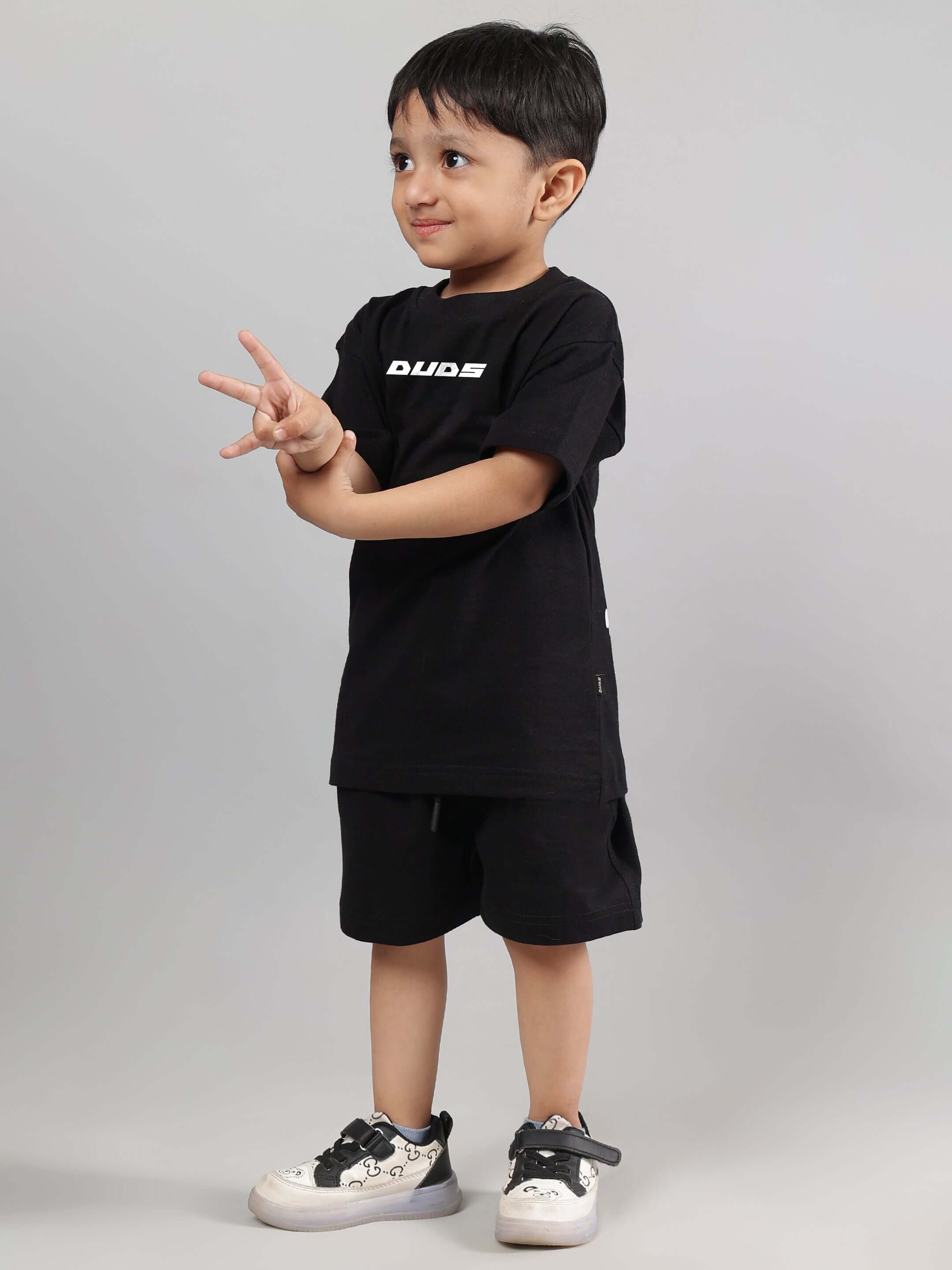 Child wearing black 'Enjoy the Wind' t-shirt by DUDS, showcasing casual style and comfort for boys and girls.