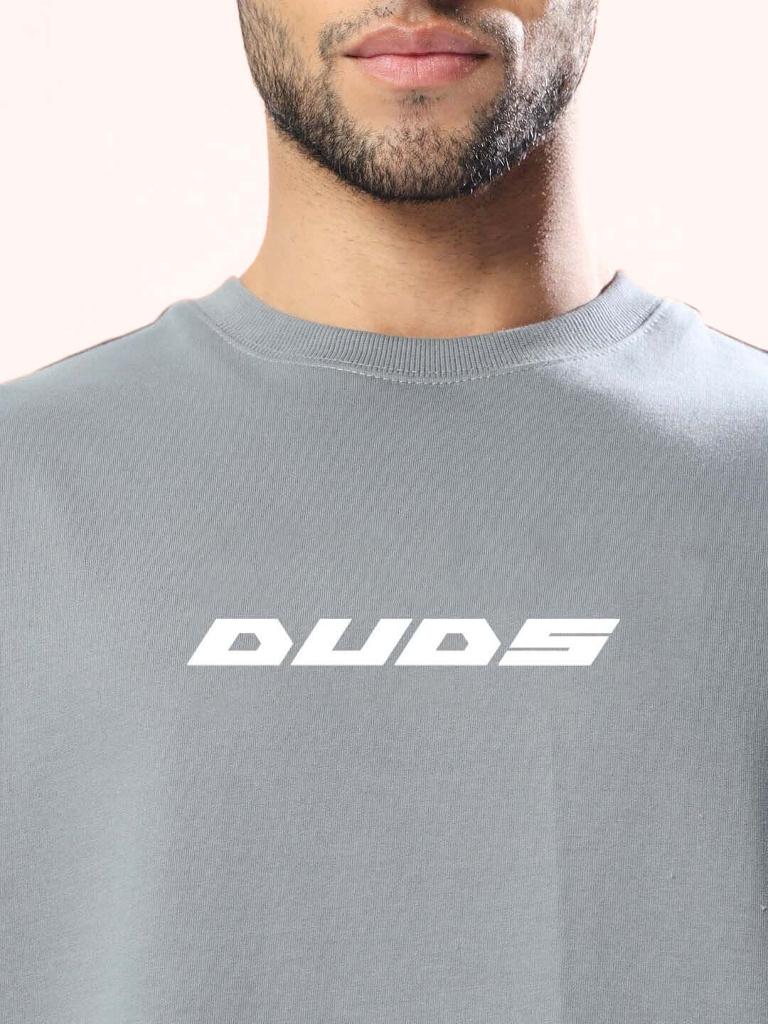 Model wearing ENJOY THE WIND over-sized grey T-shirt by DUDS, featuring a comfortable design with customizable fit options.