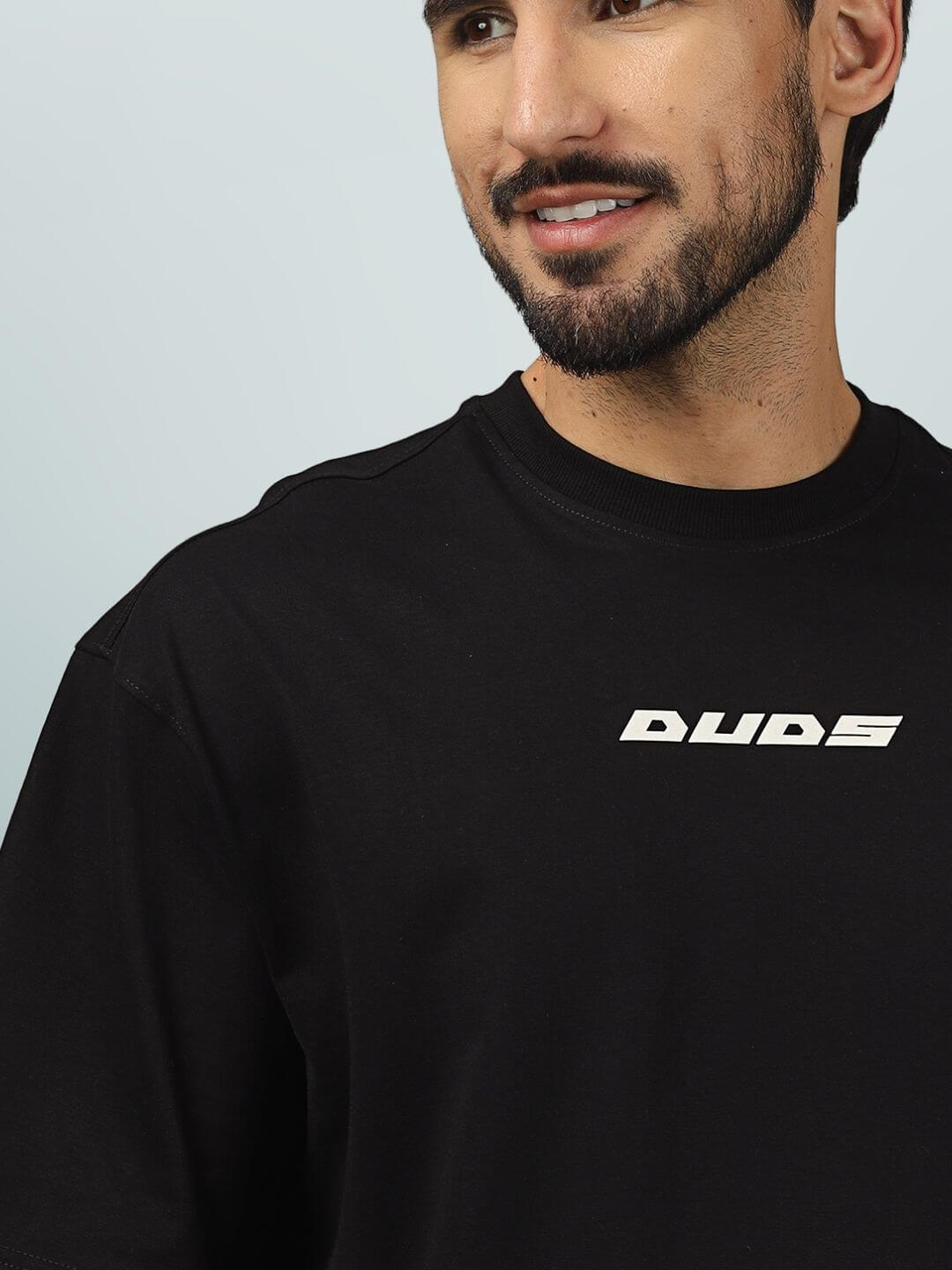 Model wearing ETCETERA oversized black T-shirt from DUDS with logo print; custom fit option available for prepaid orders.