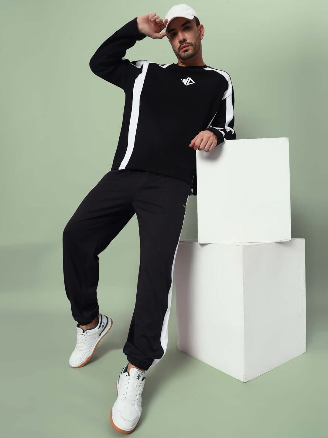 Man wearing Euphoria Joggers in Black-White with casual sneakers, posed against a modern geometric setup.