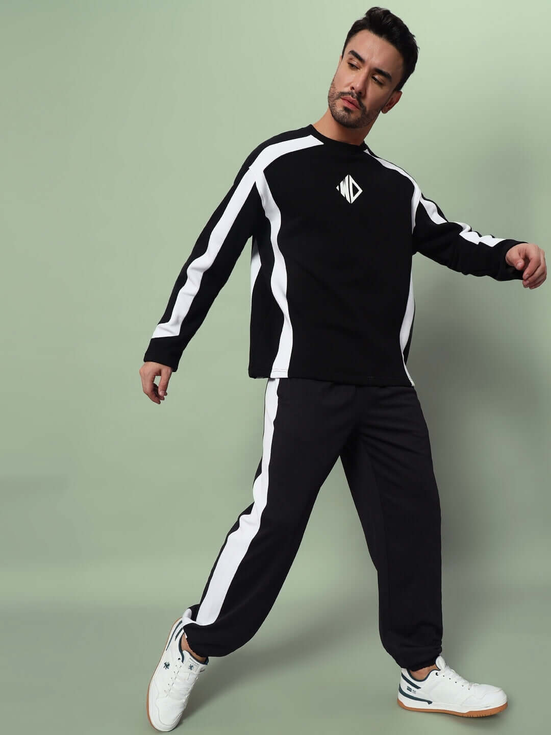 Man wearing black and white Euphoria joggers and matching top, posing confidently against a pastel green background.
