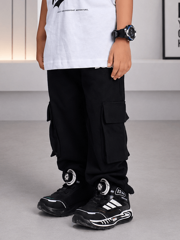 Boy wearing EVERYDAY ADVENTURE JOGGER FOR BOYS GIRLS BLACK with stylish sneakers and a watch.