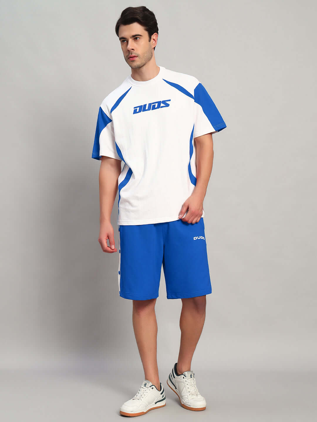 Man wearing EZEL REGULAR FIT COTTON SHORTS BLUE with matching t-shirt and sneakers, showcasing casual style for warm days.