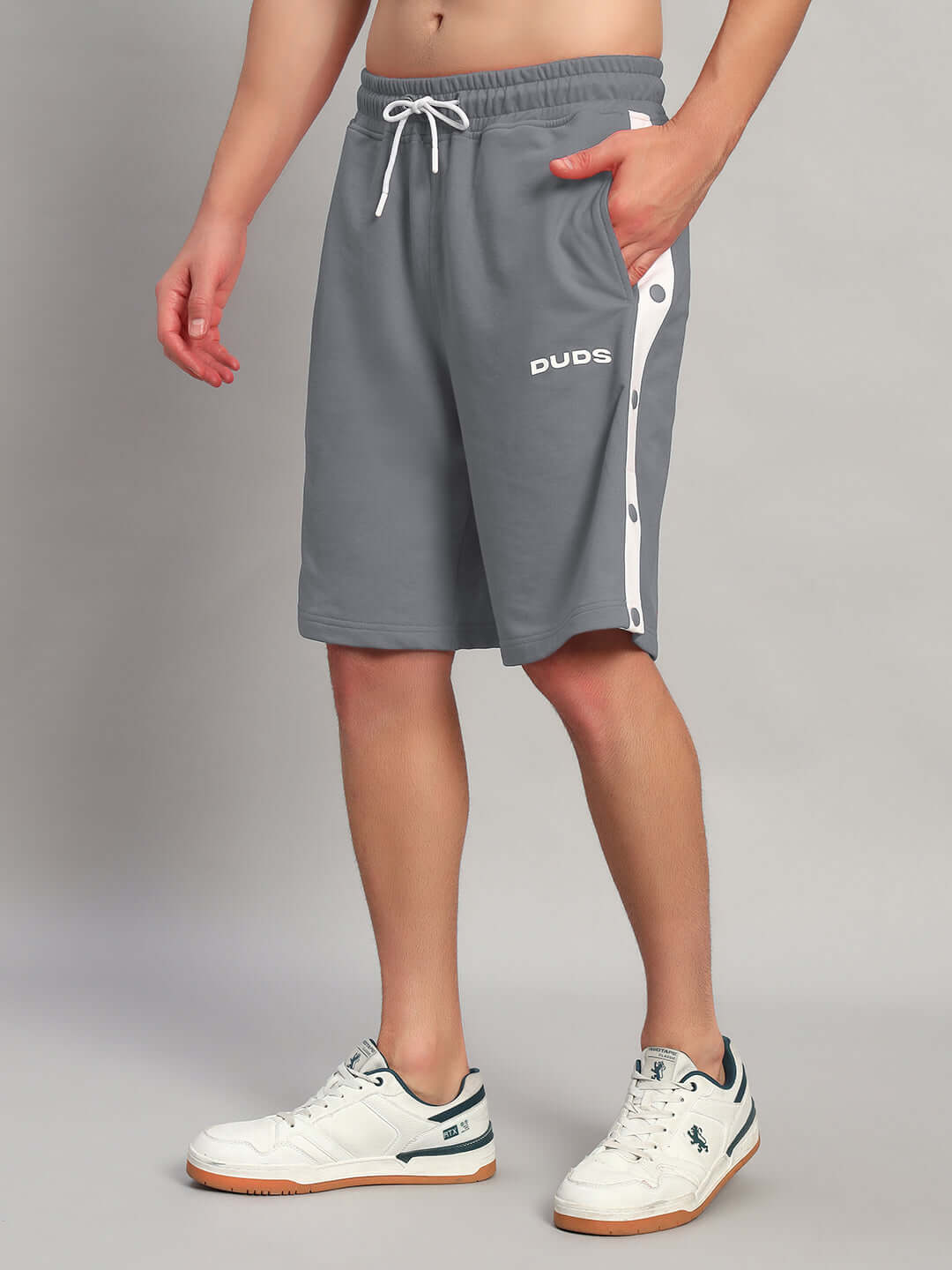 Man wearing EZEL REGULAR FIT COTTON SHORTS GREY with white sneakers; comfortable and stylish for casual outings.