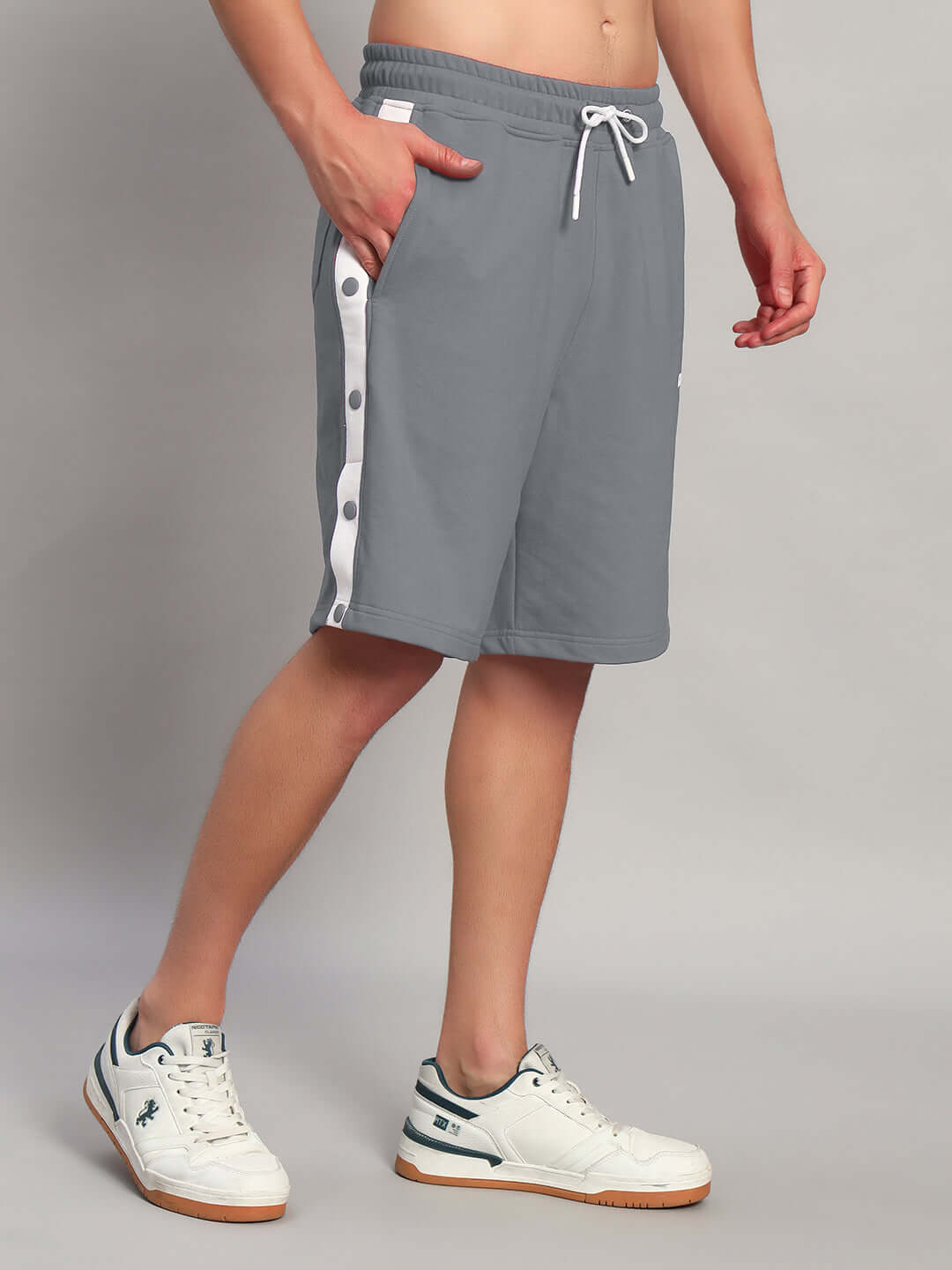 Person wearing EZEL REGULAR FIT COTTON SHORTS GREY with white sneakers, showcasing casual and comfortable style.