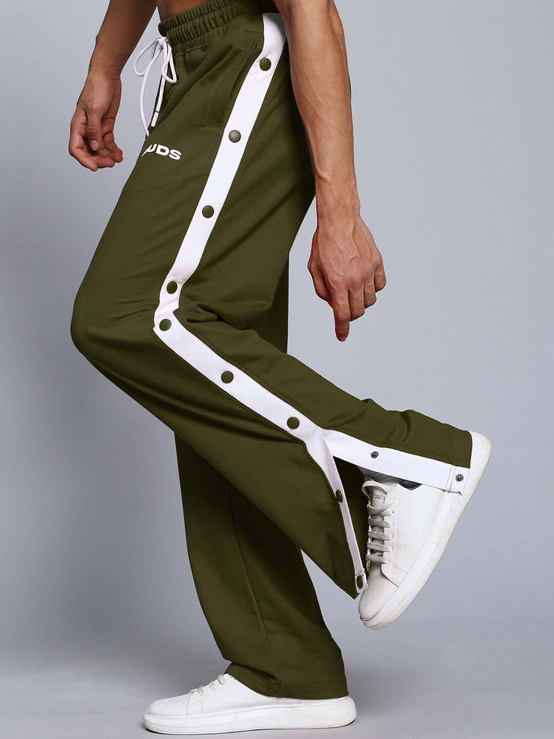 Person wearing EZEL RELAXED FIT CO-ORD SET WHITE-OLIVE pants with button detail and white sneakers.