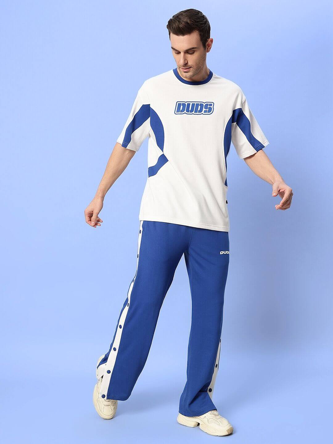Man wearing EZEL RELAXED FIT CO-ORD SET WHITE-BLUE with sporty design against blue background.