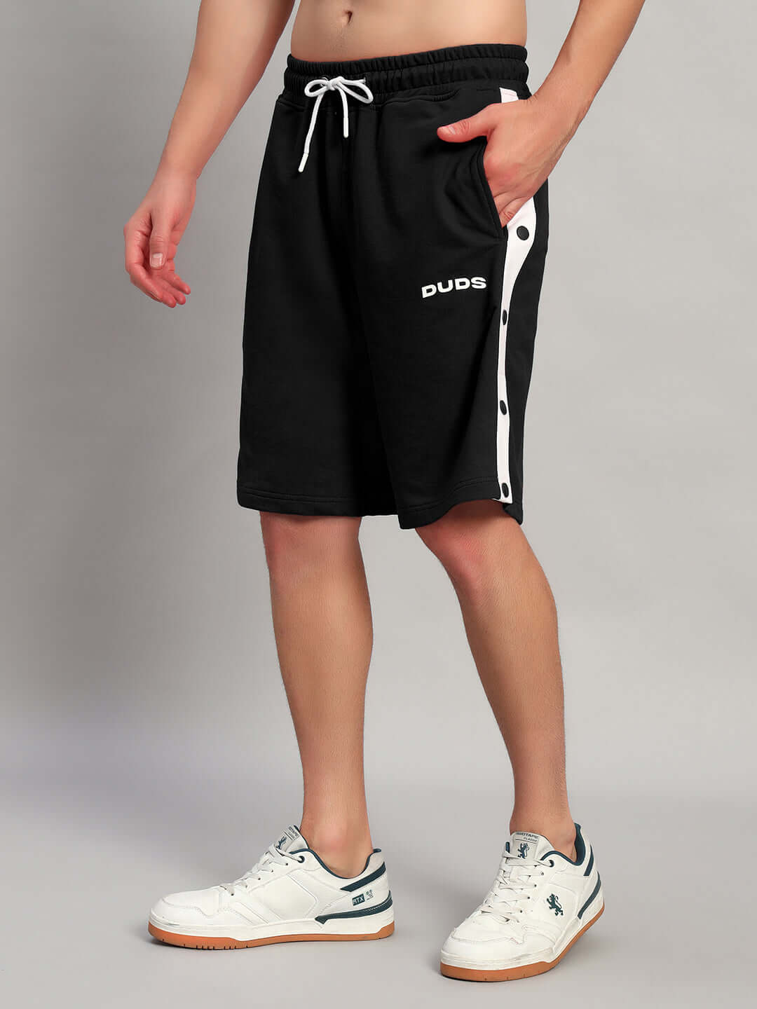 Man wearing EZEL REGULAR FIT SHORTS BLACK cotton, casual streetwear style with white sneakers.