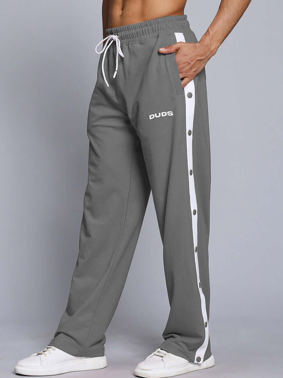 Model wearing EZEL relaxed fit jogger in grey by DUDS, featuring side buttons and drawstring waist, customizable size available.