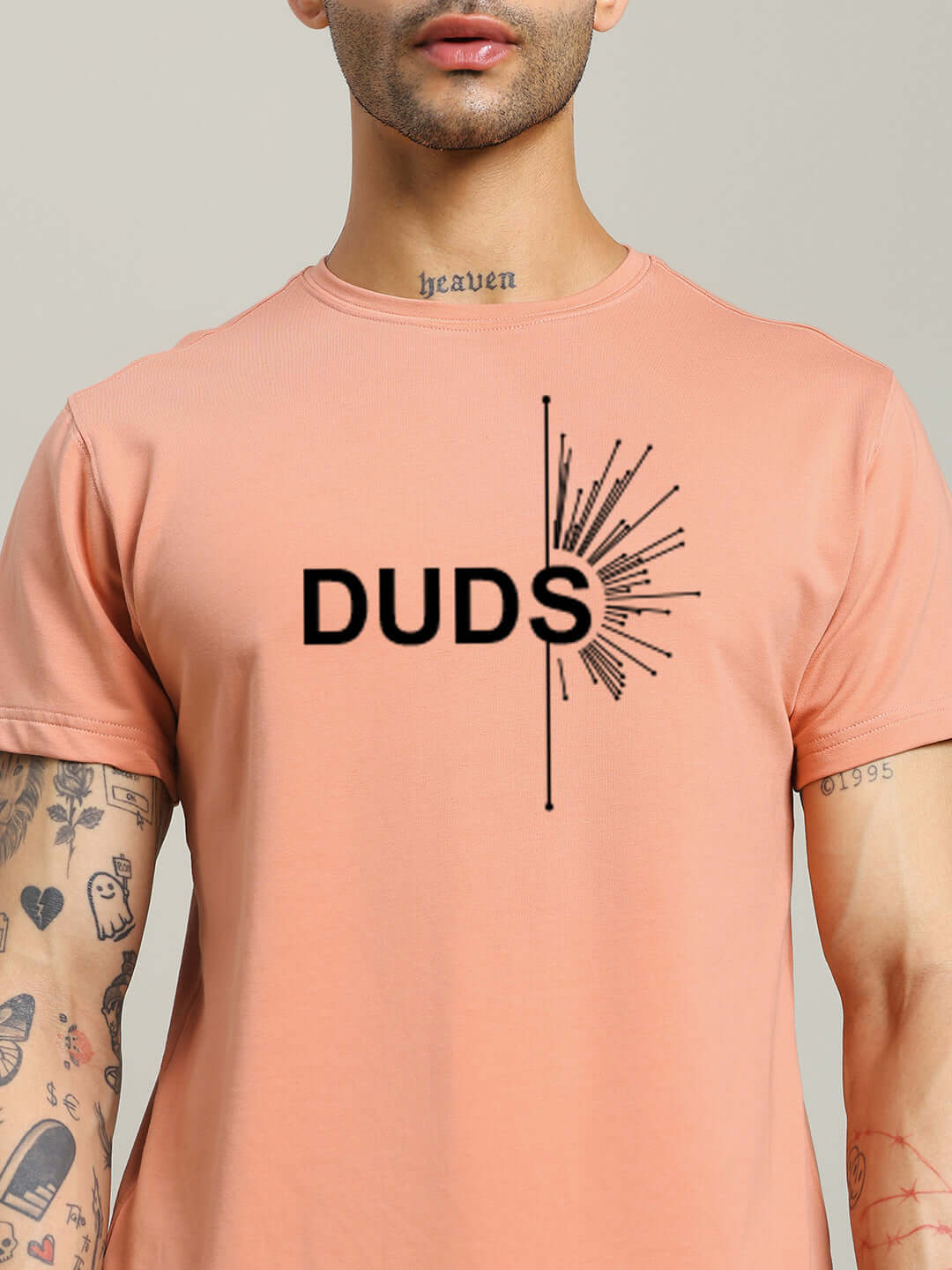Peach Fallen Angle Regular Fit T-Shirt with "DUDS" graphic design, 100% cotton, modeled by tattooed person.